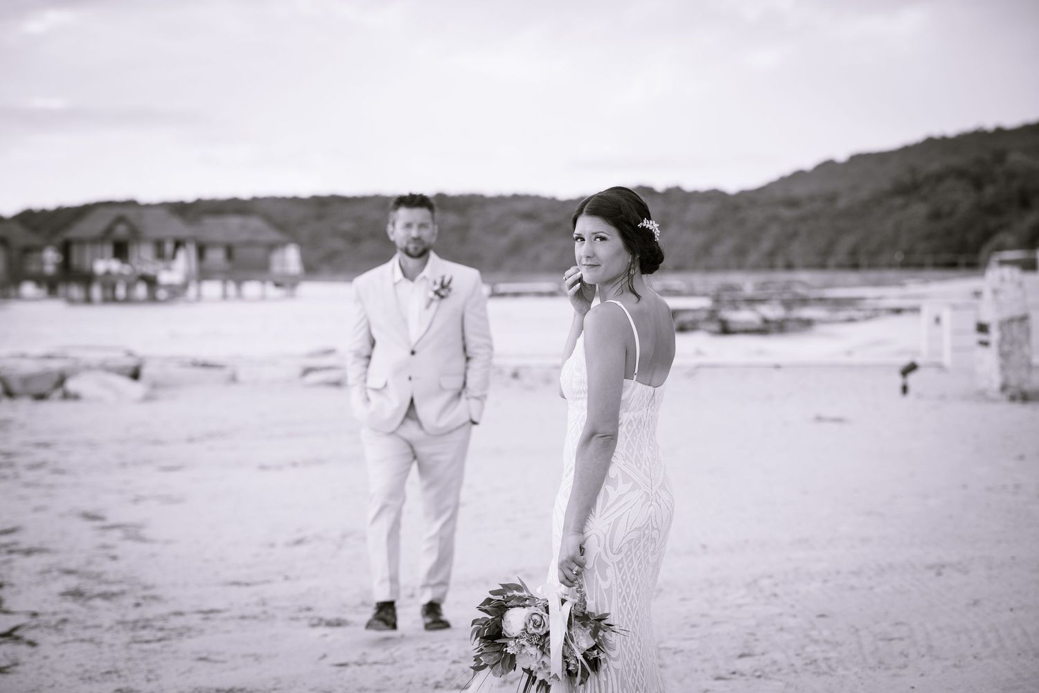 A romantic couple in white attire shares intimate moments during their beach wedding photoshoot.