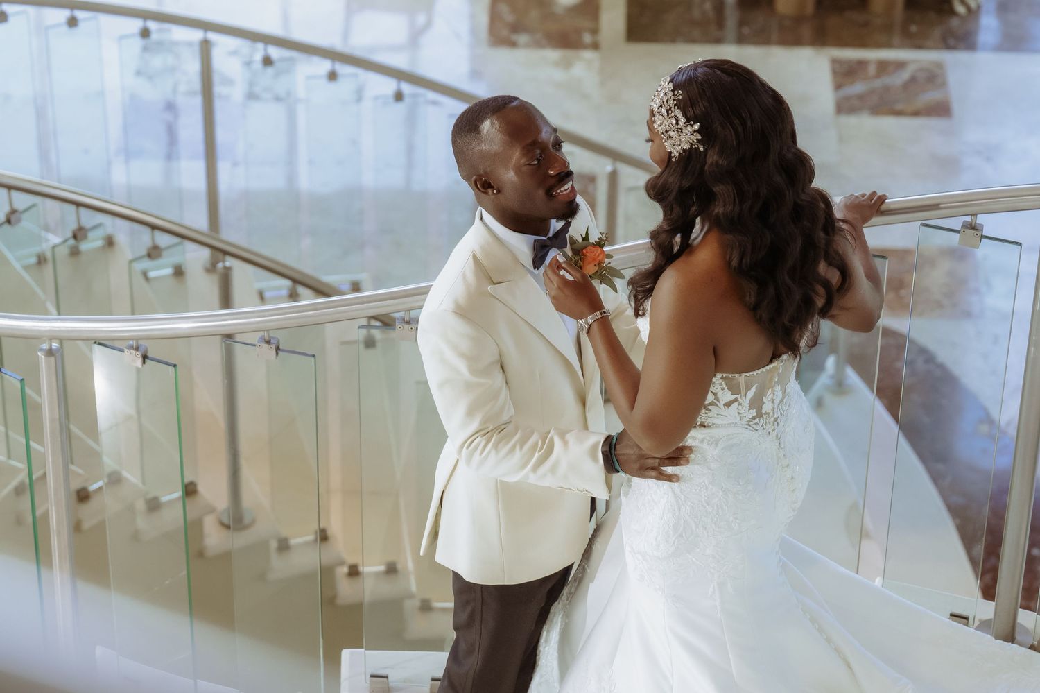 A romantic moment captured between newlyweds on an elegant staircase with glass railings.