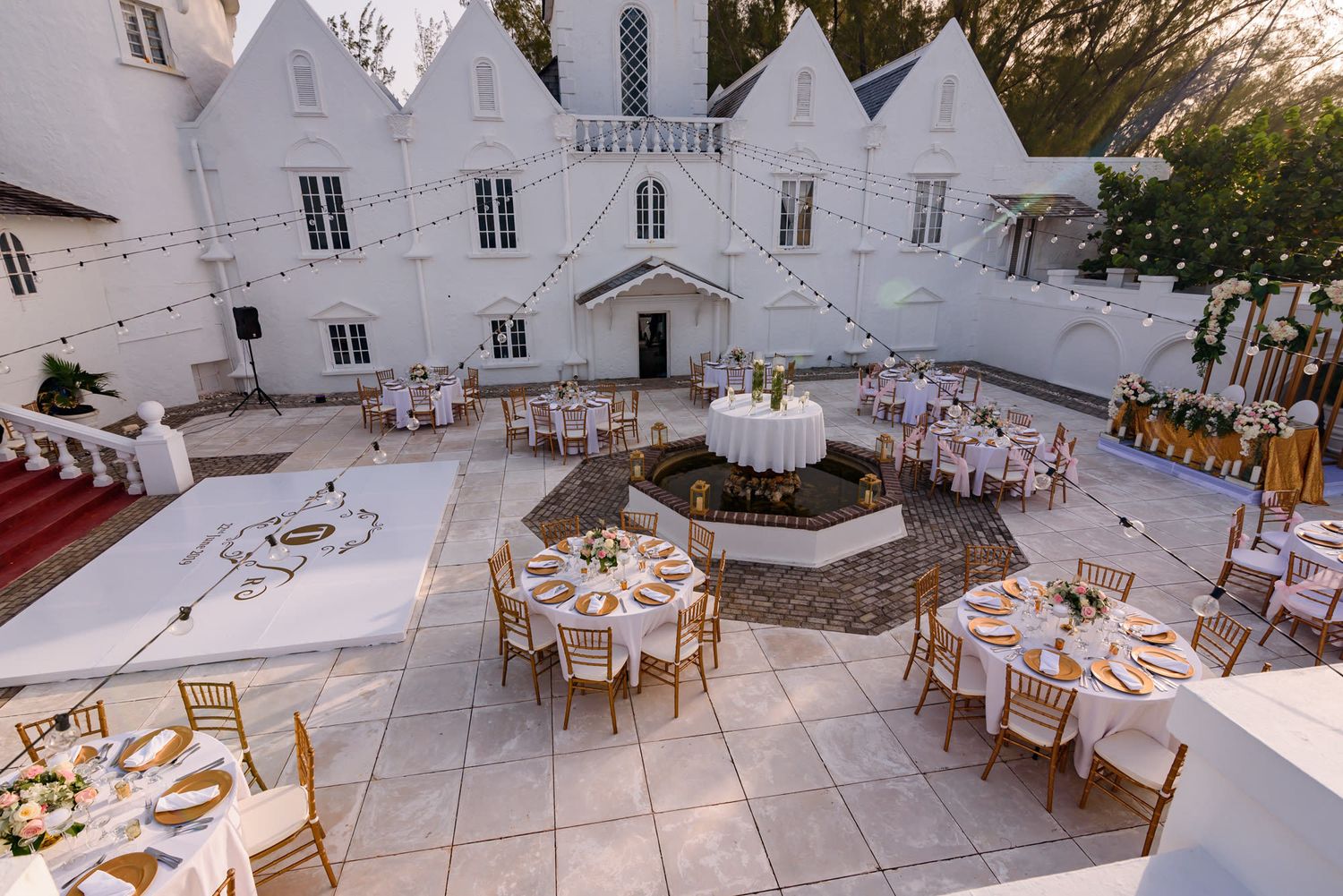 Aerial view of outdoor wedding reception setup with round tables and white chairs.