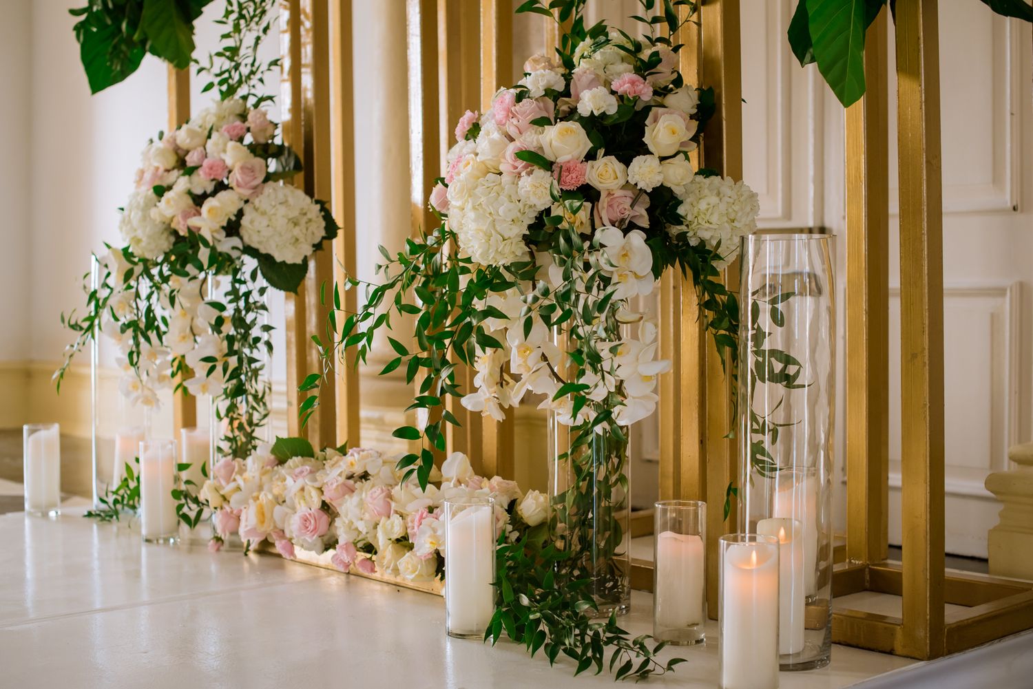 Luxurious wedding ceremony space adorned with pink and white floral arrangements and greenery.