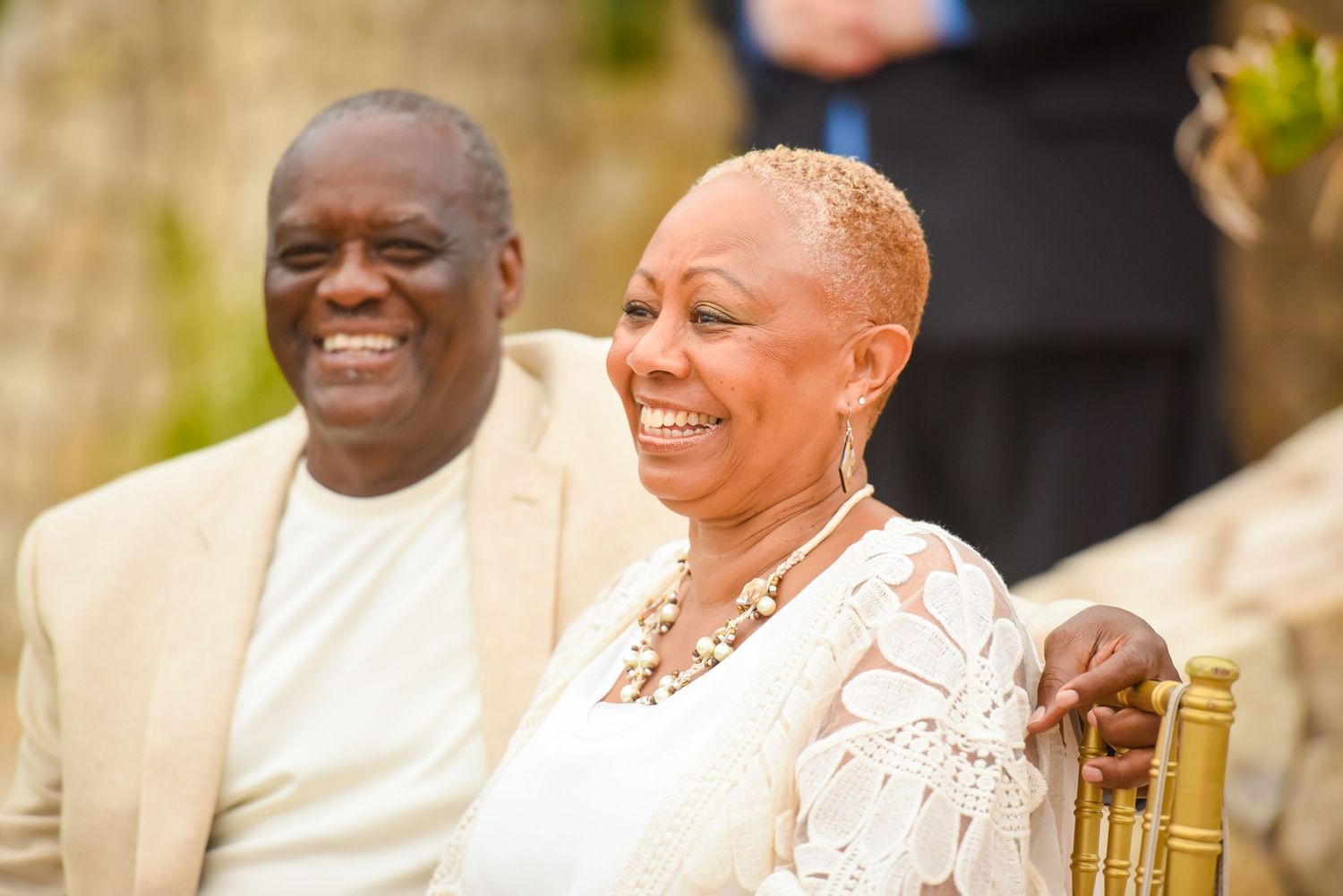 Wedding guests seated outdoors sharing joyful laughter during celebration.