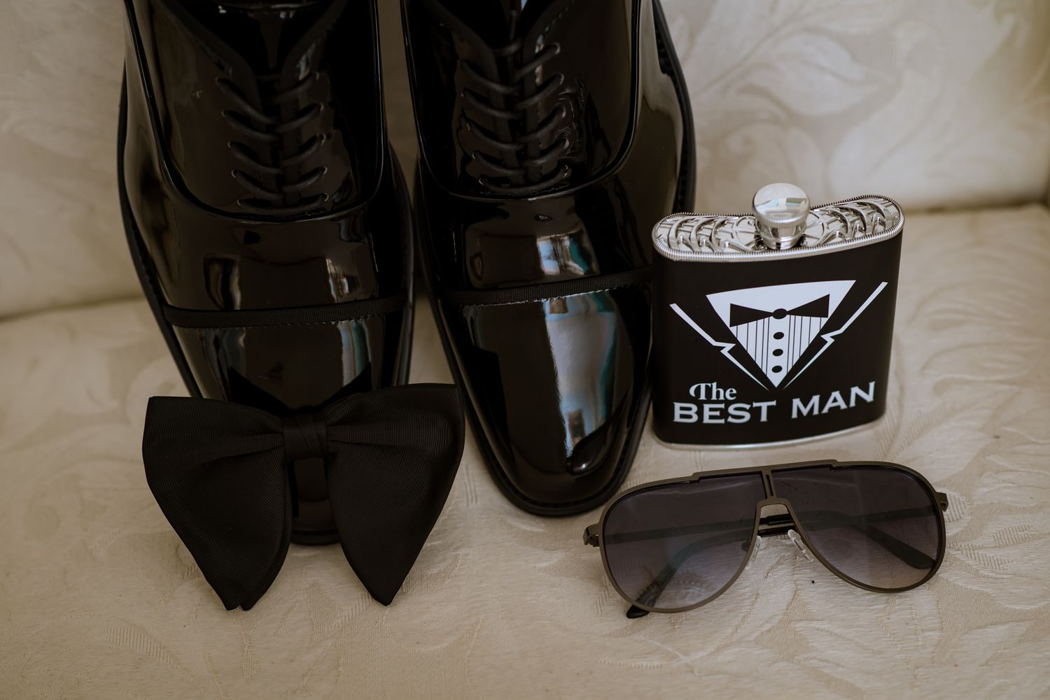 A collection of formal black dress shoes and sunglasses arranged neatly on a light surface.
