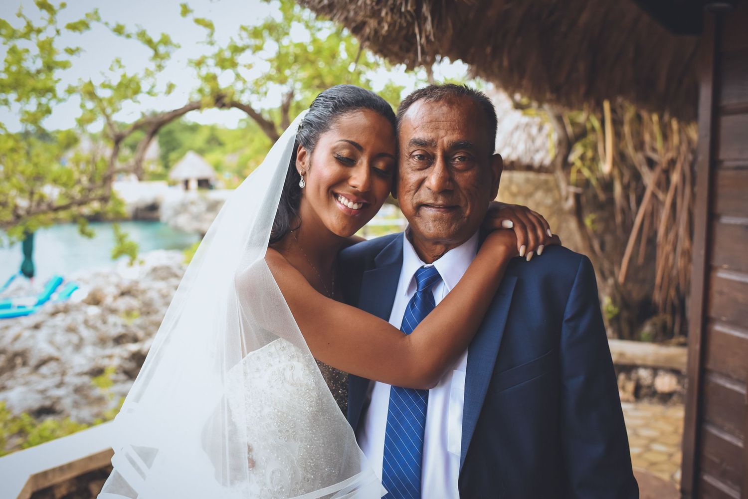 Joyful wedding portraits captured at an oceanside venue with lush greenery.