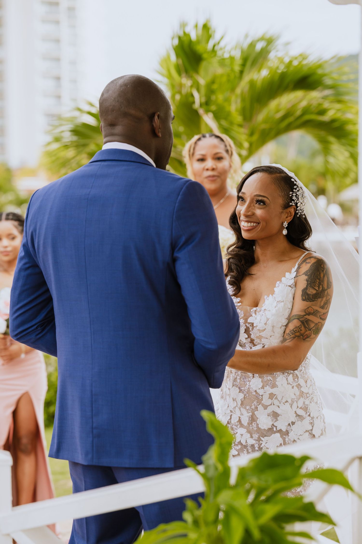A beautiful outdoor wedding ceremony with palm trees and white decorative elements.