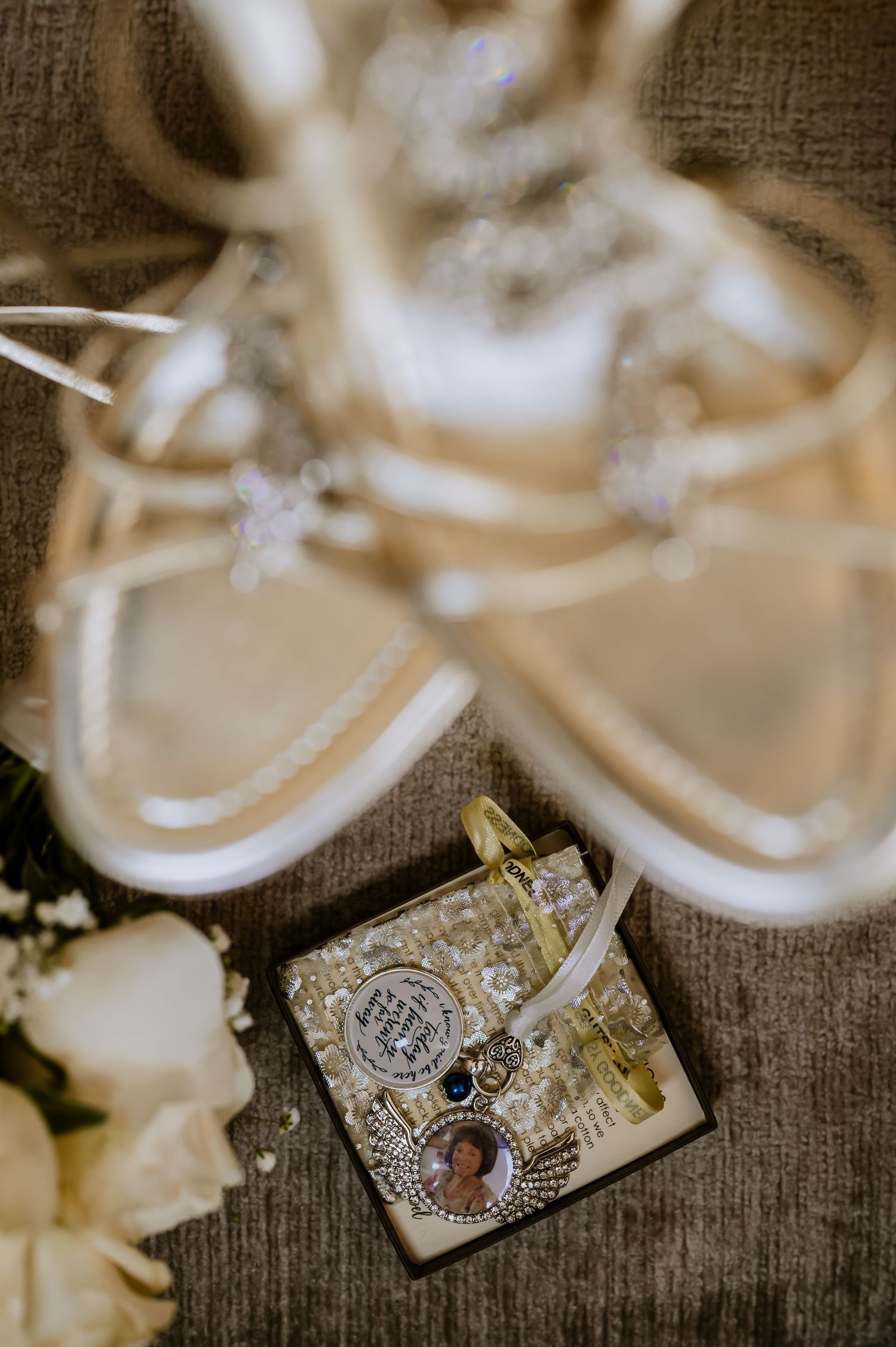 Artistic detail shot of wedding sandals with vintage-style locket and roses.