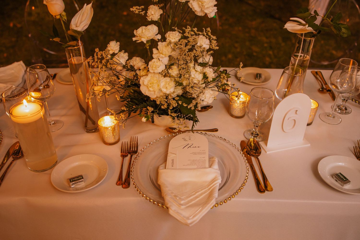 Intimate wedding table setting with white florals, candlelight, and elegant place settings.