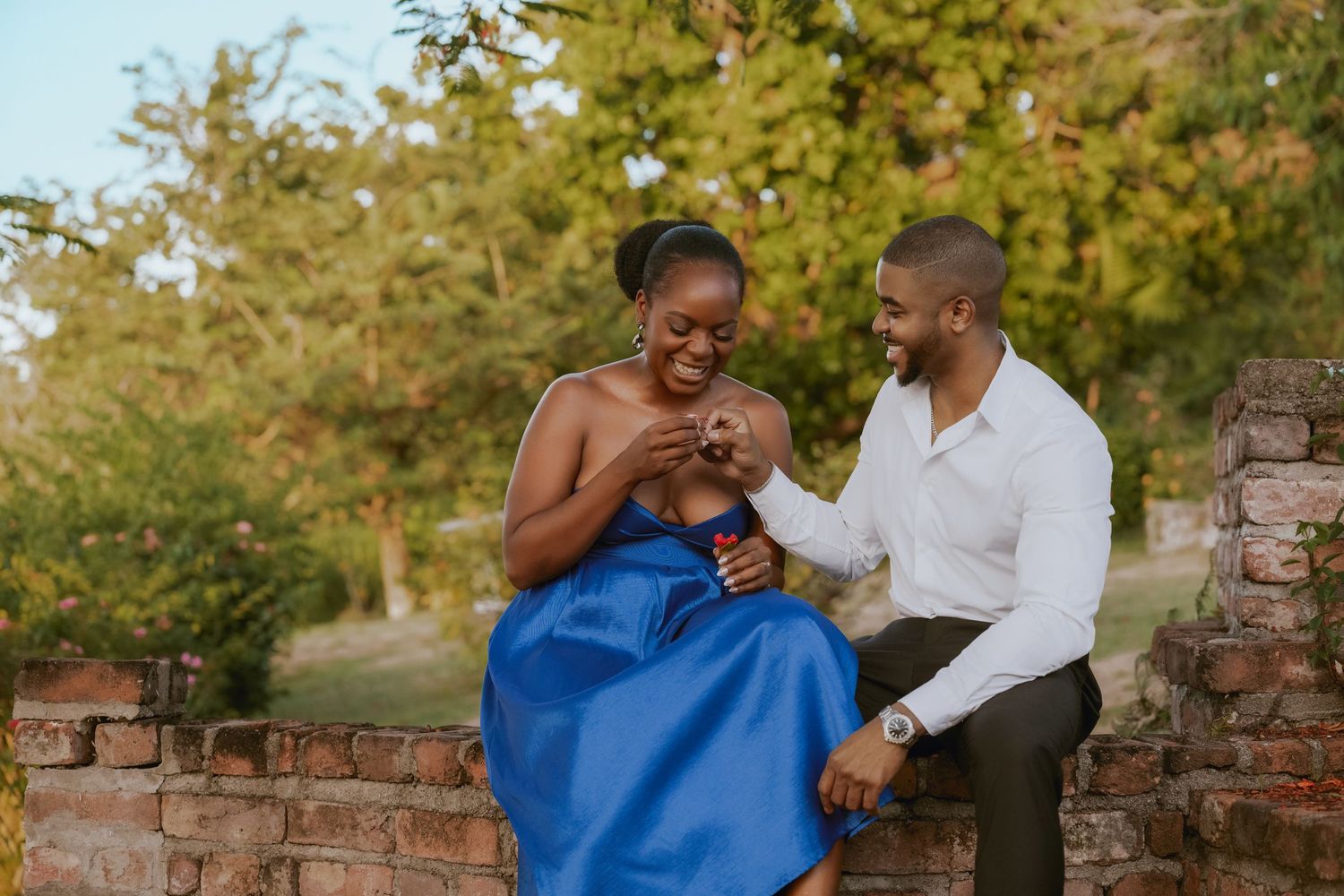 Couple sharing tender moment on garden path with brick wall.