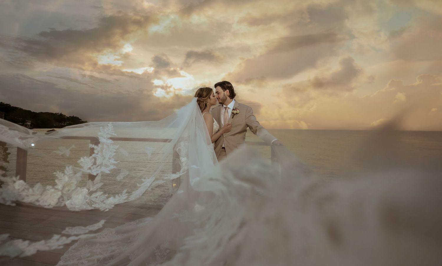 A romantic coastal wedding portrait with dramatic sunset and flowing dress.