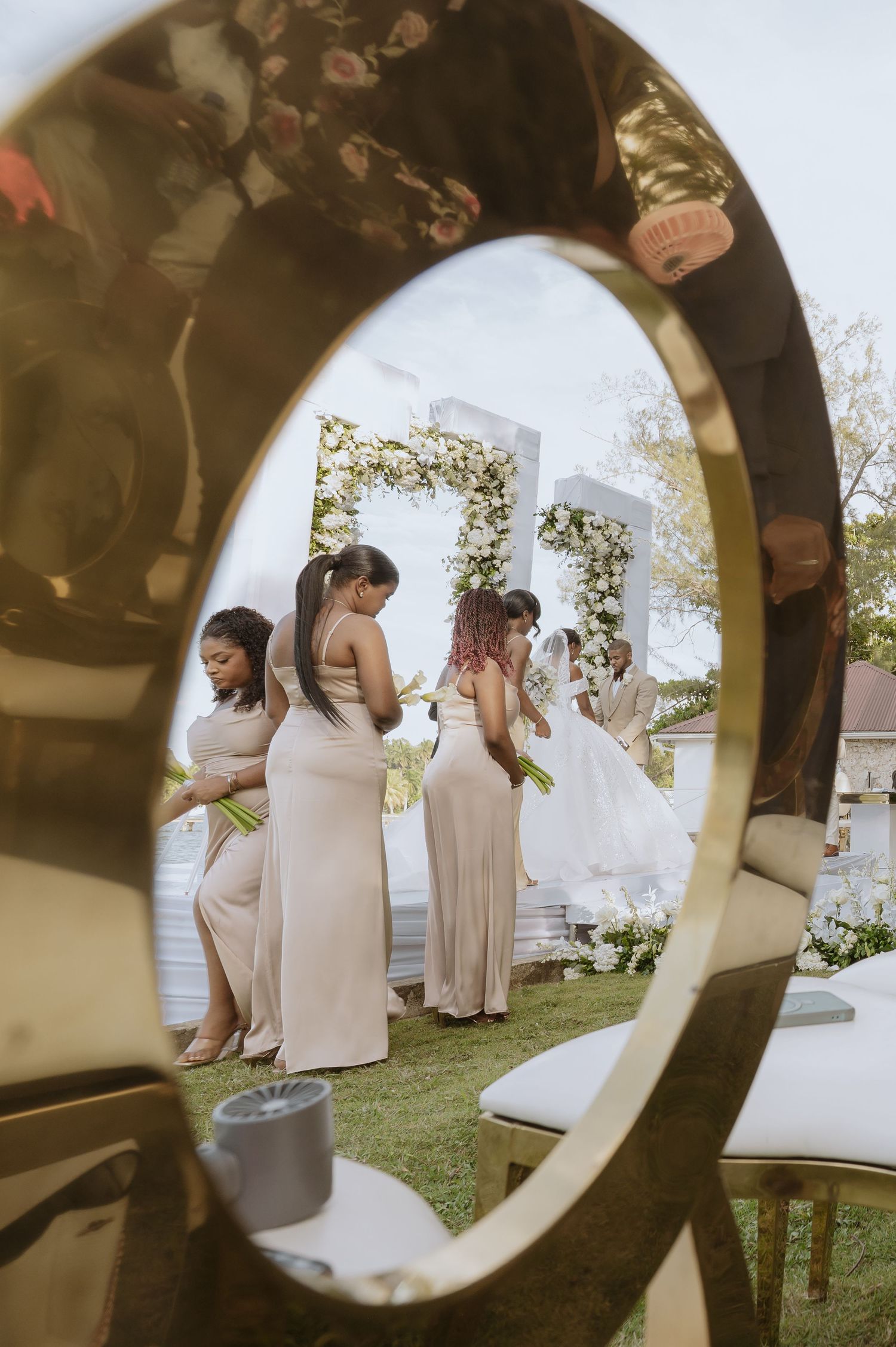Wedding party in blush pink dresses poses together outdoors through a circular frame.