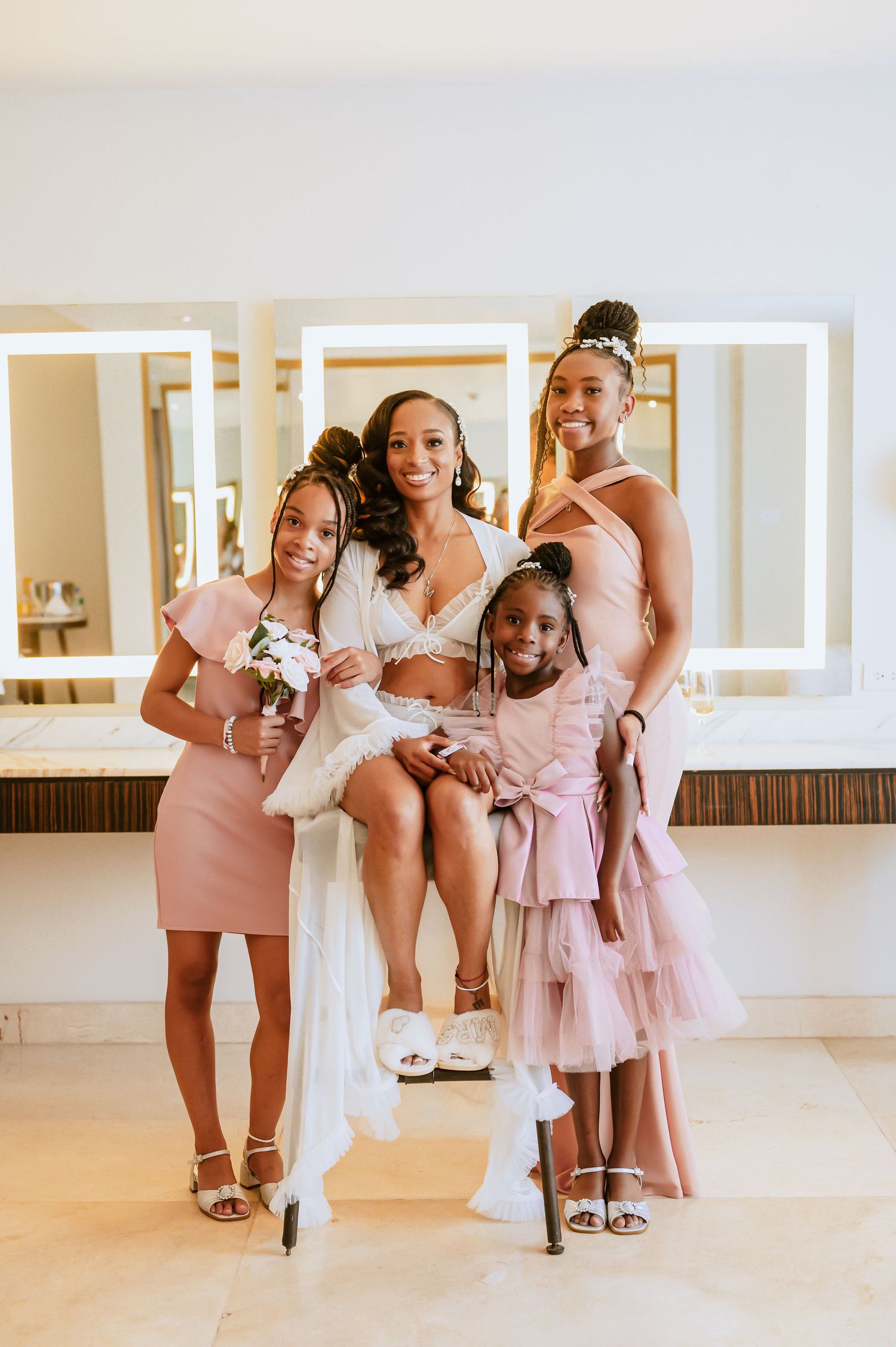 Bridesmaids in pink dresses share a fun candid moment together.