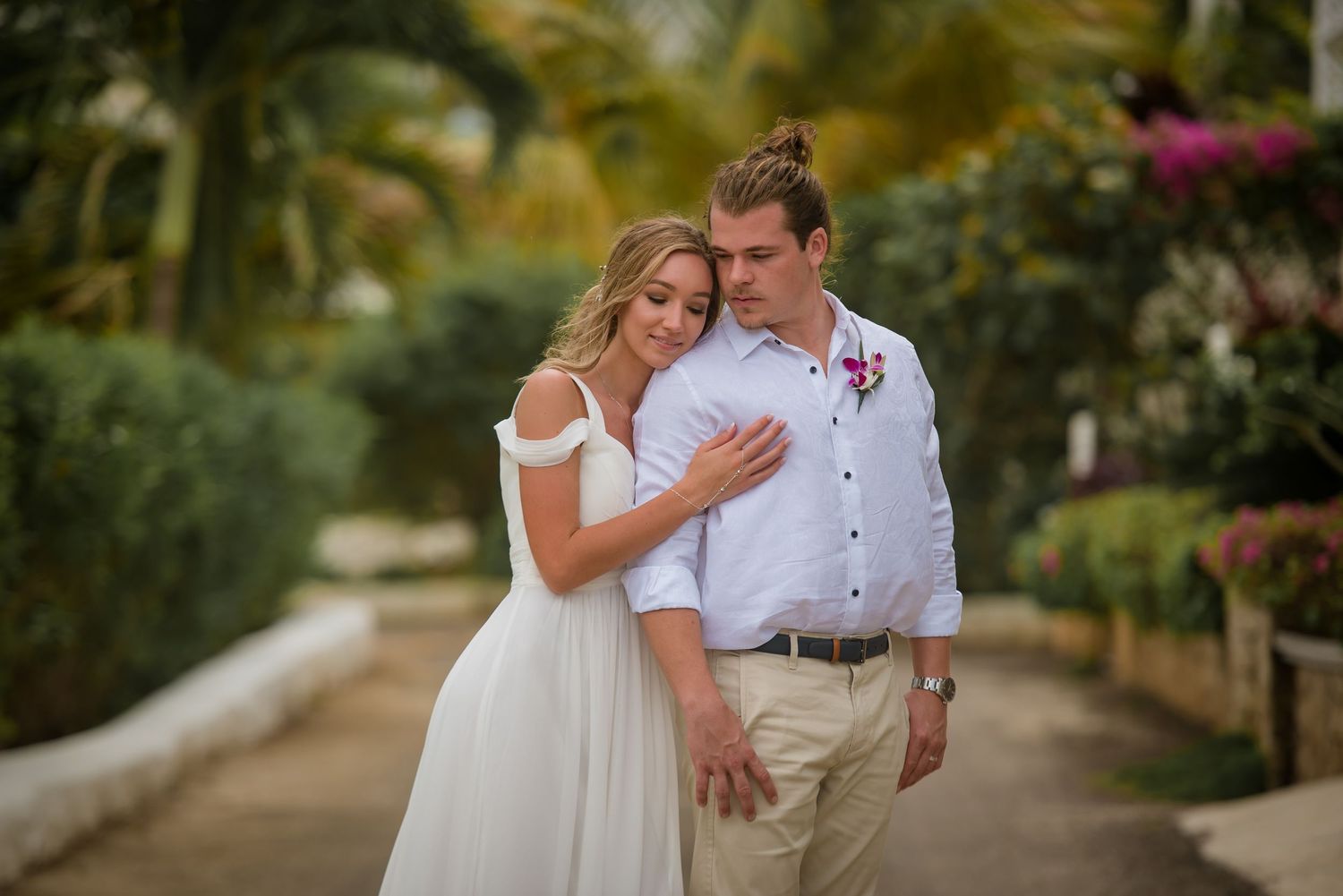 Newlyweds share romantic moments in lush garden setting during wedding photoshoot.