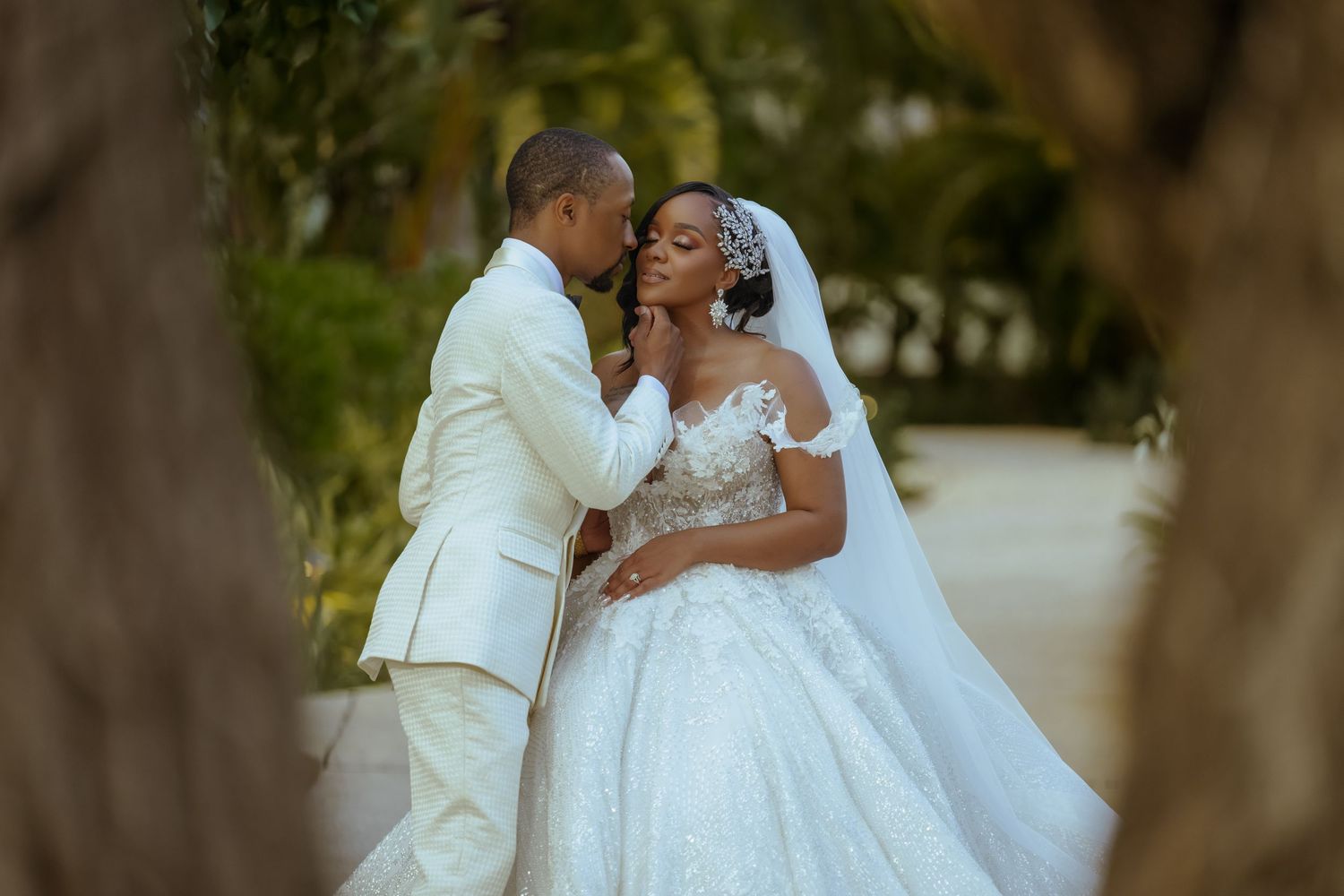 A romantic wedding couple shares tender moments in a garden setting while wearing white formal attire.half-moon-montego-bay-wedding-photogra