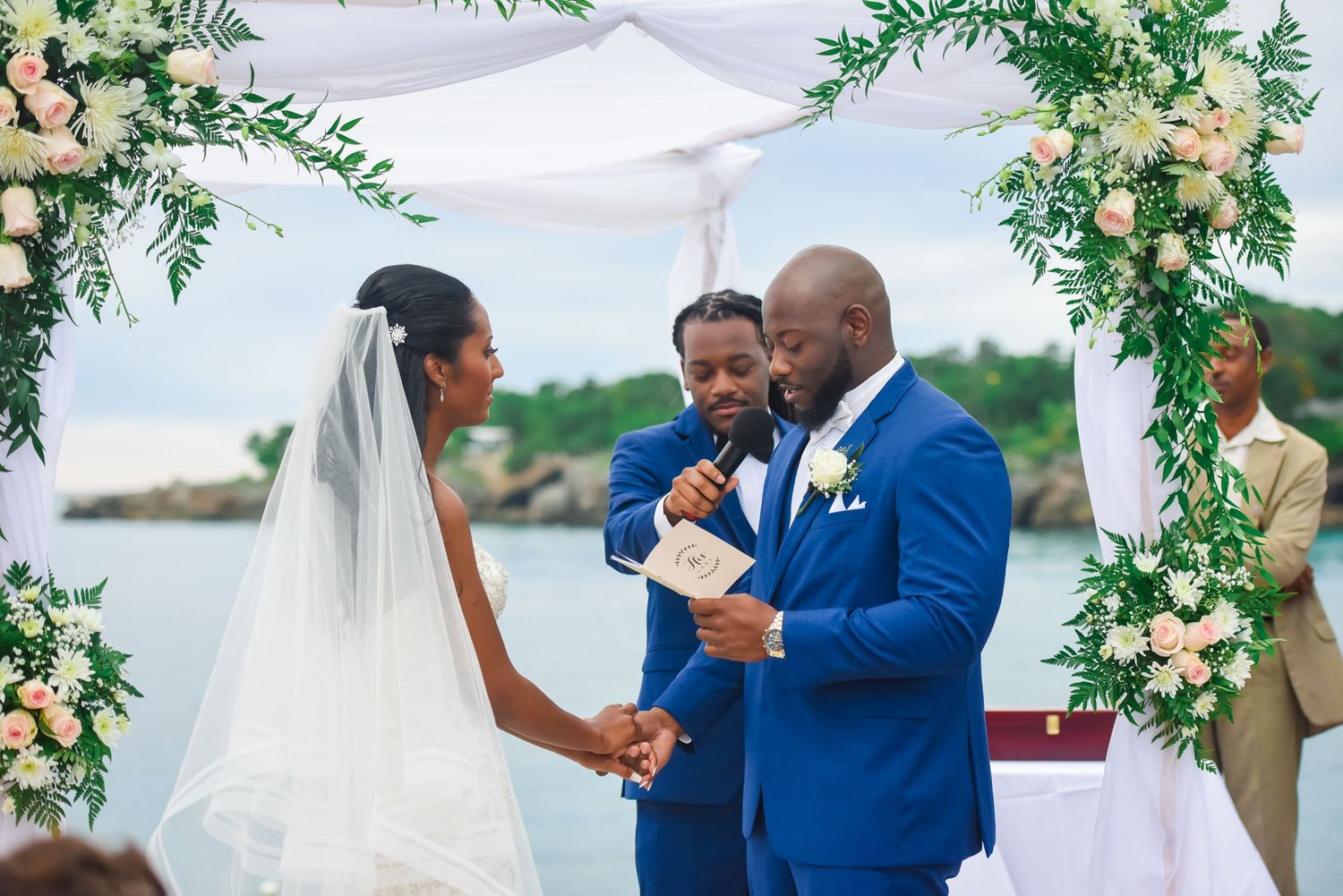 Wedding ceremony under floral arch with greenery and white flowers.