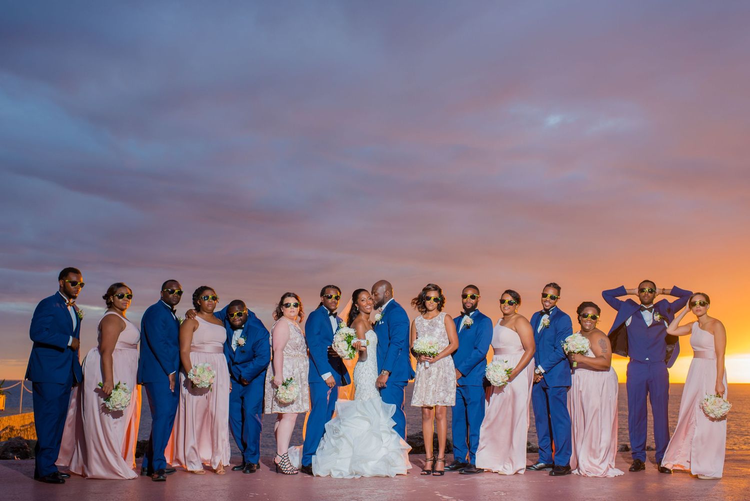 Wedding party poses together during golden hour with dramatic sky backdrop.