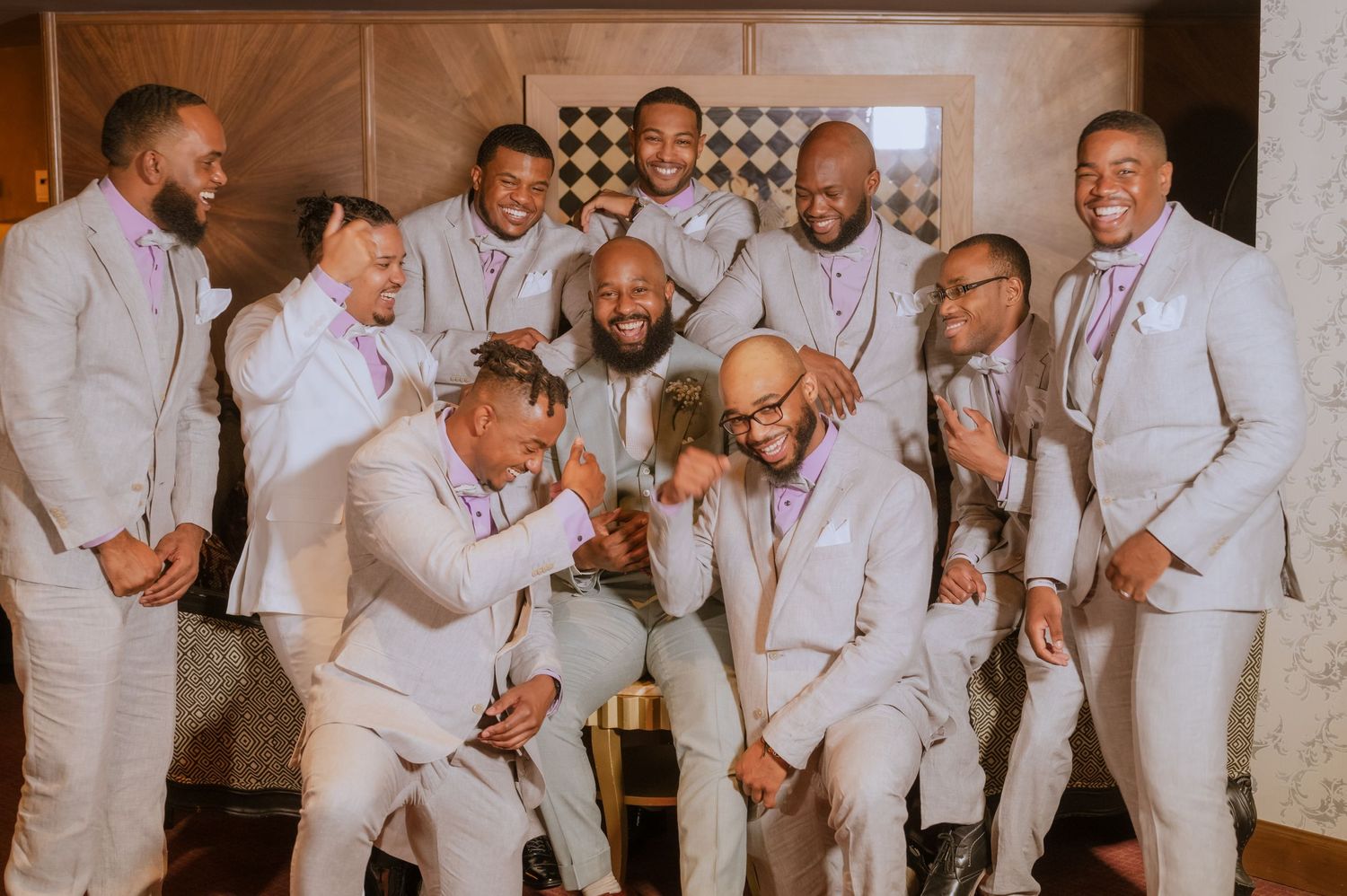 Groomsmen in coordinated attire gather for candid moments at wedding celebration.