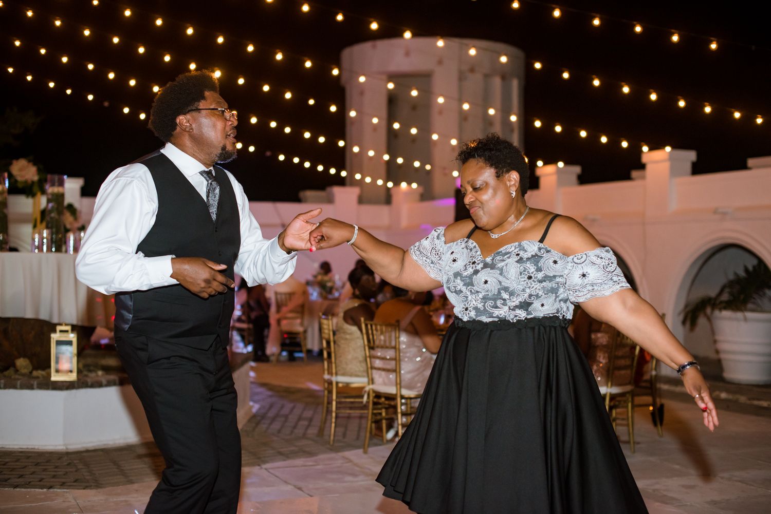 Wedding reception under warm string lights with guests enjoying the evening.