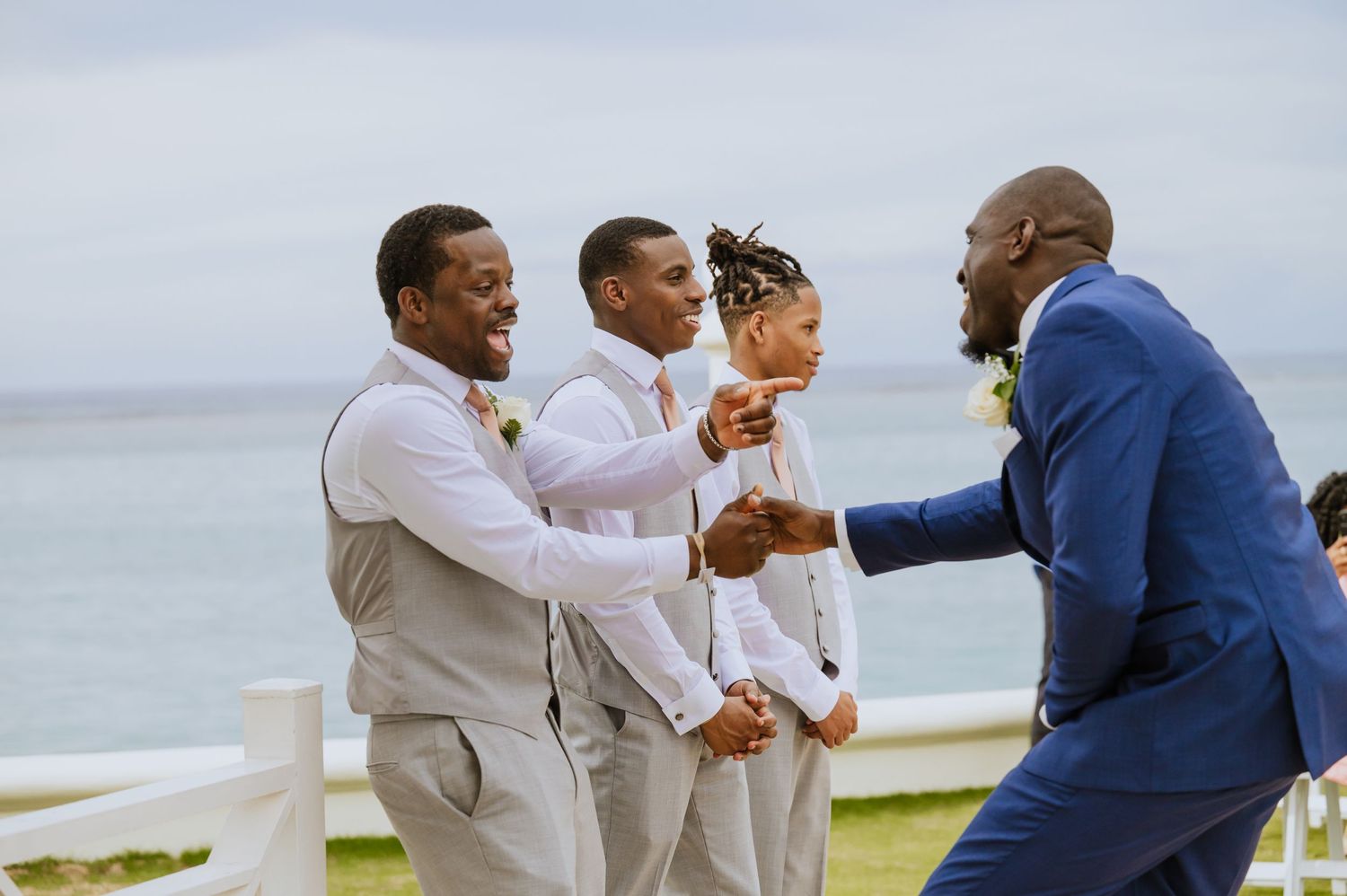 Wedding party members interact and celebrate on oceanfront path.