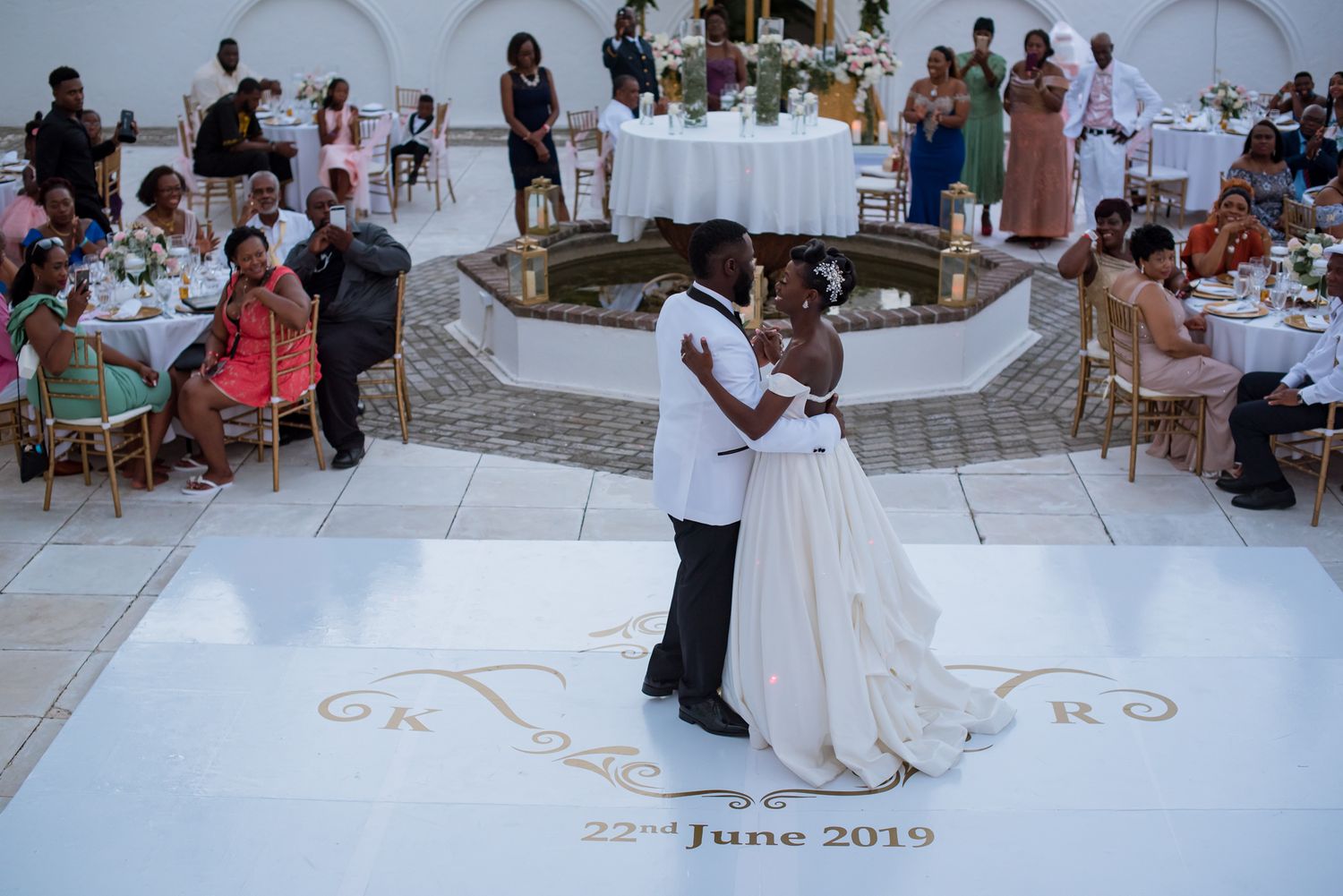 Outdoor wedding celebration with guests gathered around a dance floor.