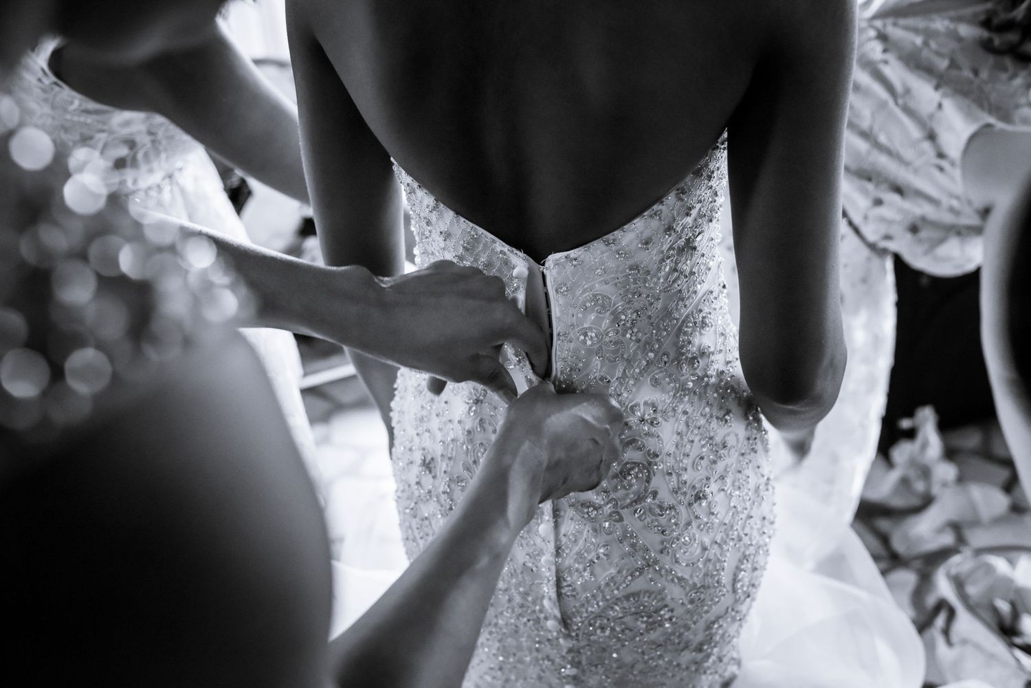Close-up details of intricate beading and lace on a white wedding gown.