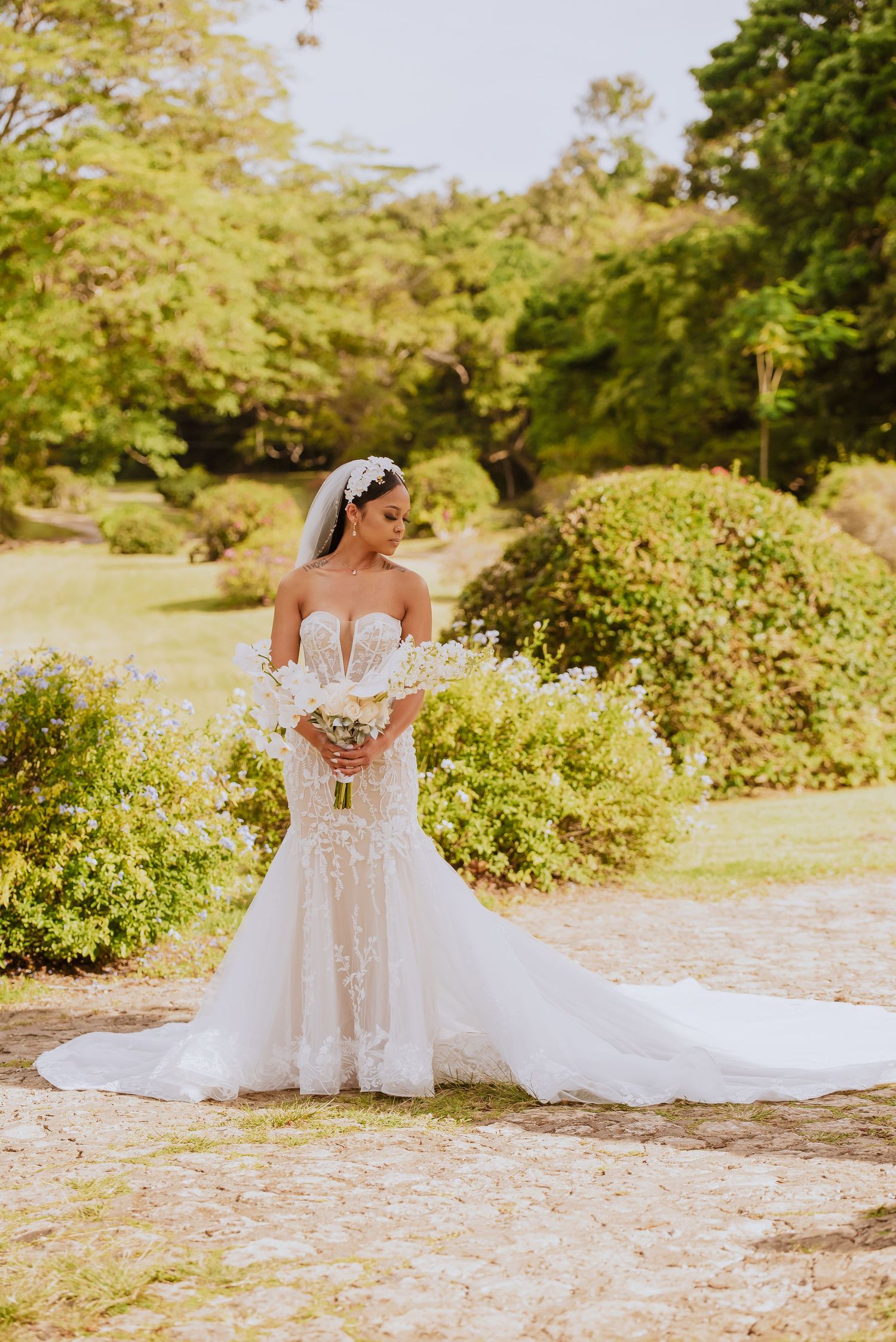 Beautiful white wedding gown with lace details captured in a sunlit garden setting.