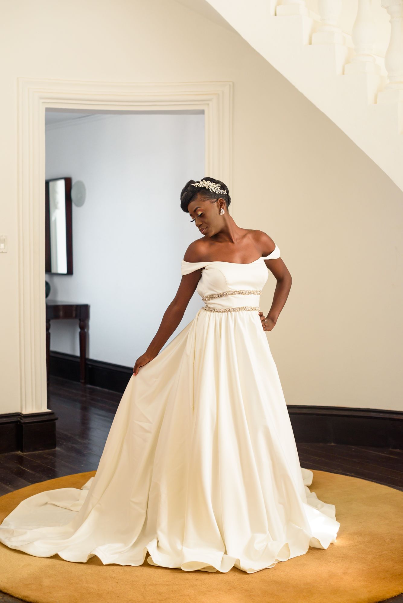 A person in a stunning white wedding gown poses elegantly in a bright room.