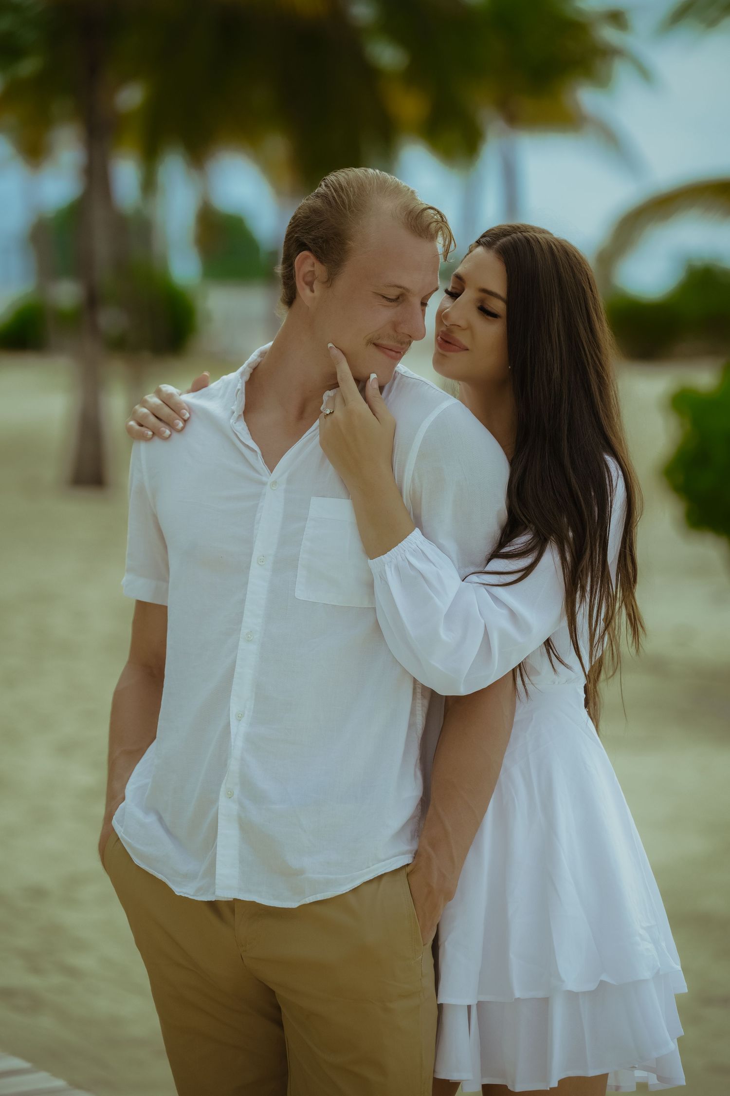 Tender moments captured between a couple in white clothing during their beach photoshoot.