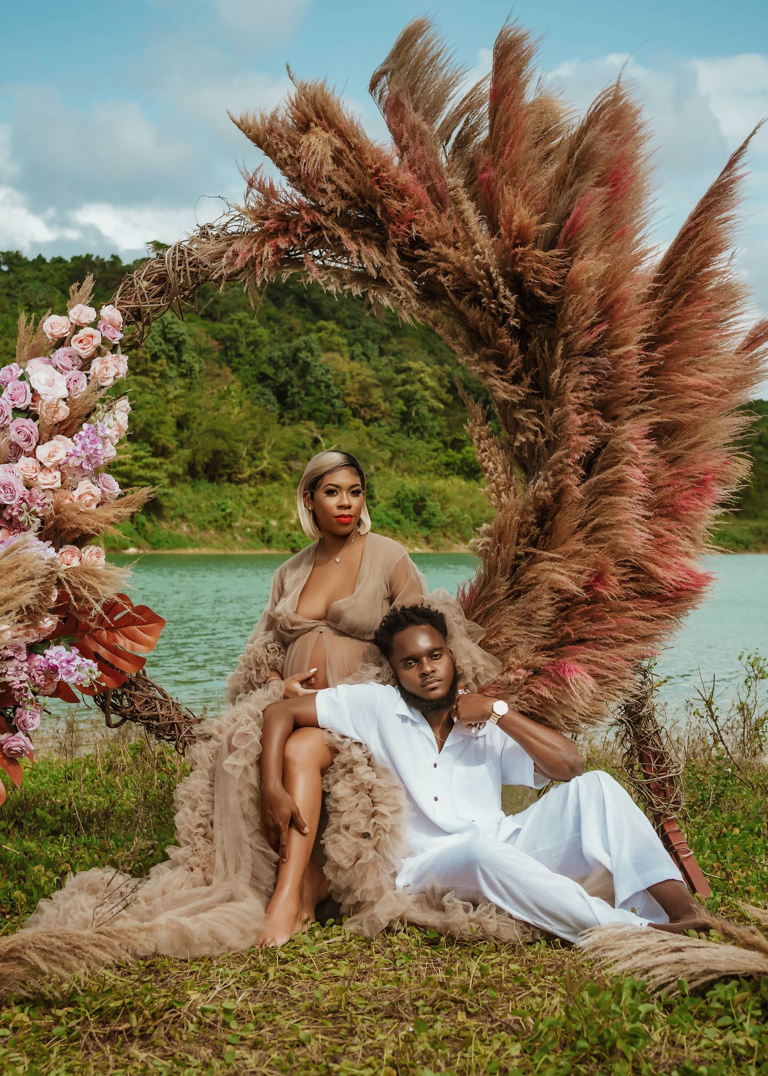 Romantic photoshoot setup by a lake with pampas grass and pink floral decorations.