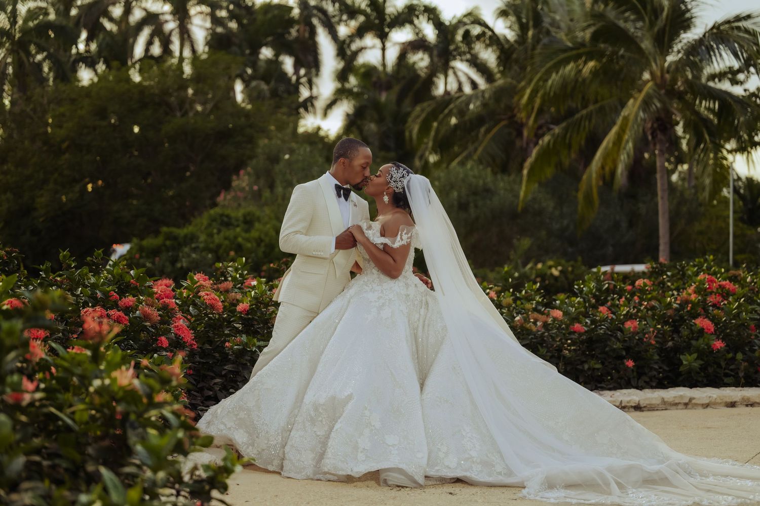A romantic beach wedding photoshoot with palm trees and tropical flowers in the background.