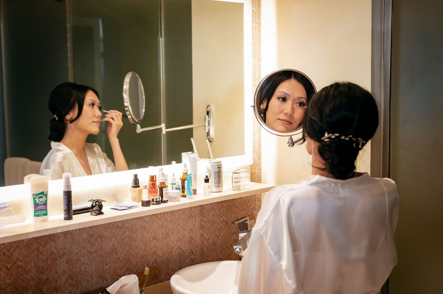 Getting ready scene with bridesmaids in a well-lit dressing room with mirrors.