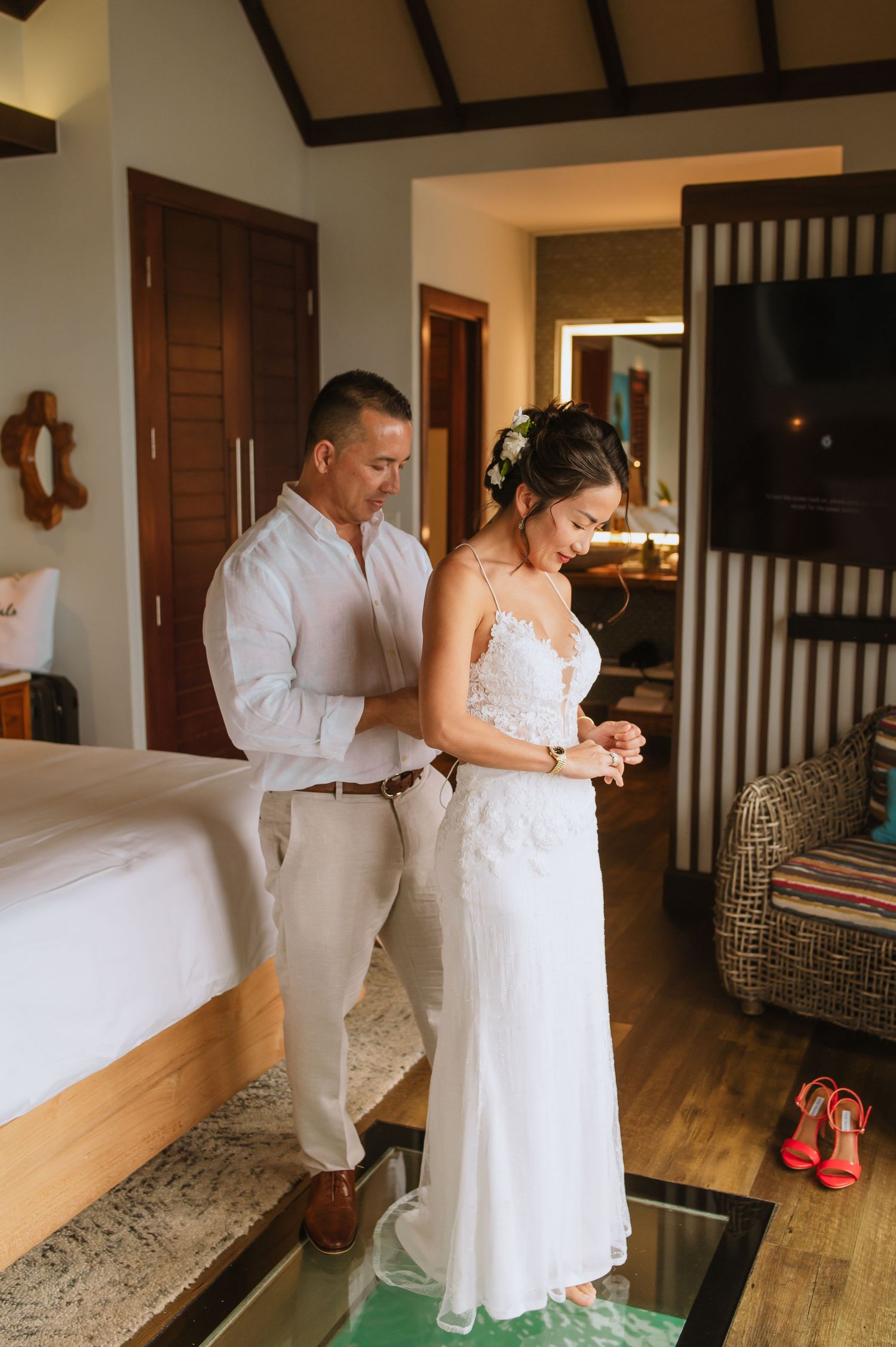 A couple gets ready in a tropical villa room with wooden interior details.