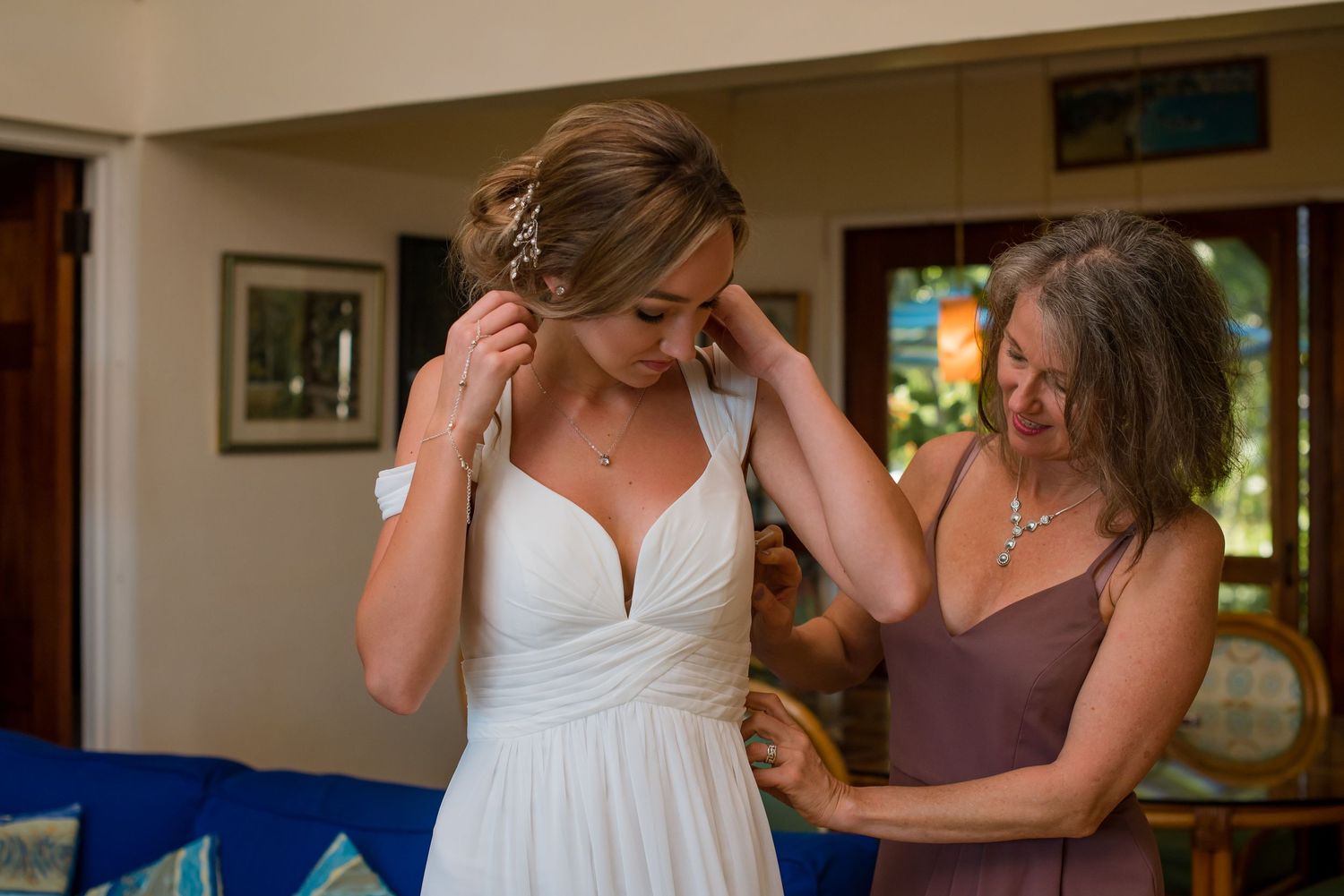 Wedding preparations showing dress adjustments in a cozy indoor setting.