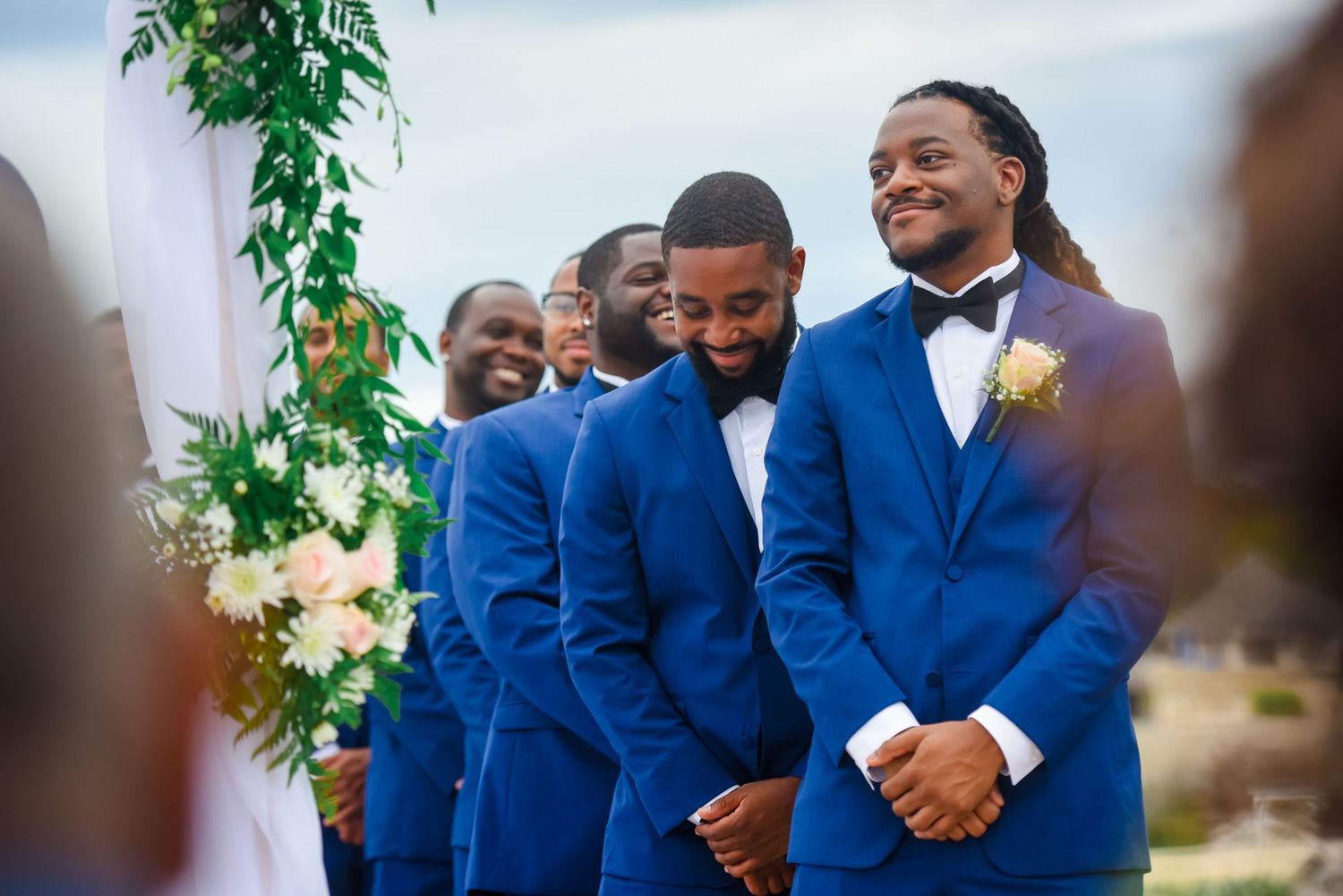 Joyful wedding ceremony moments with groomsmen in bright blue suits.