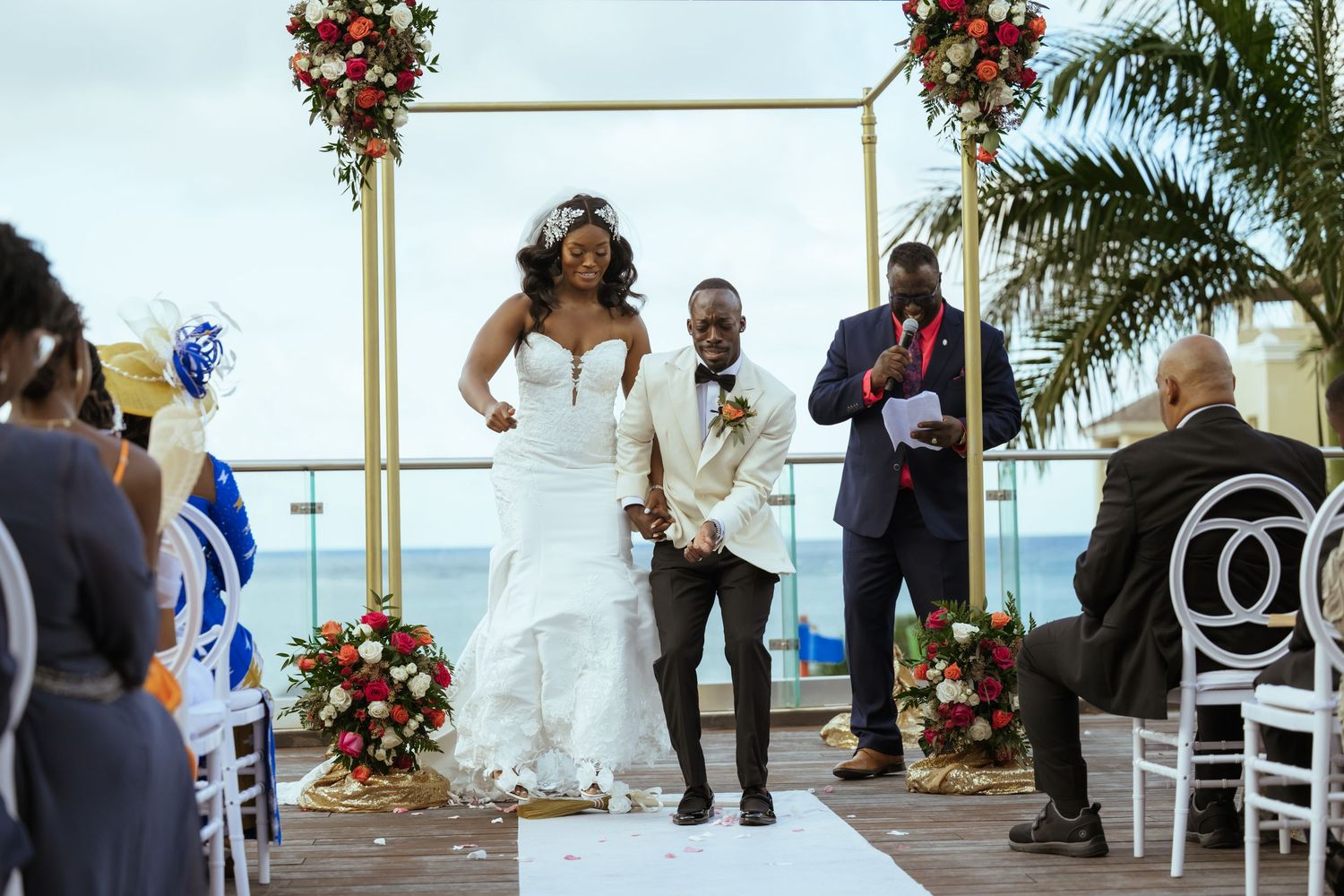 Wedding ceremony venue decorated with red roses and white chairs overlooking the ocean.