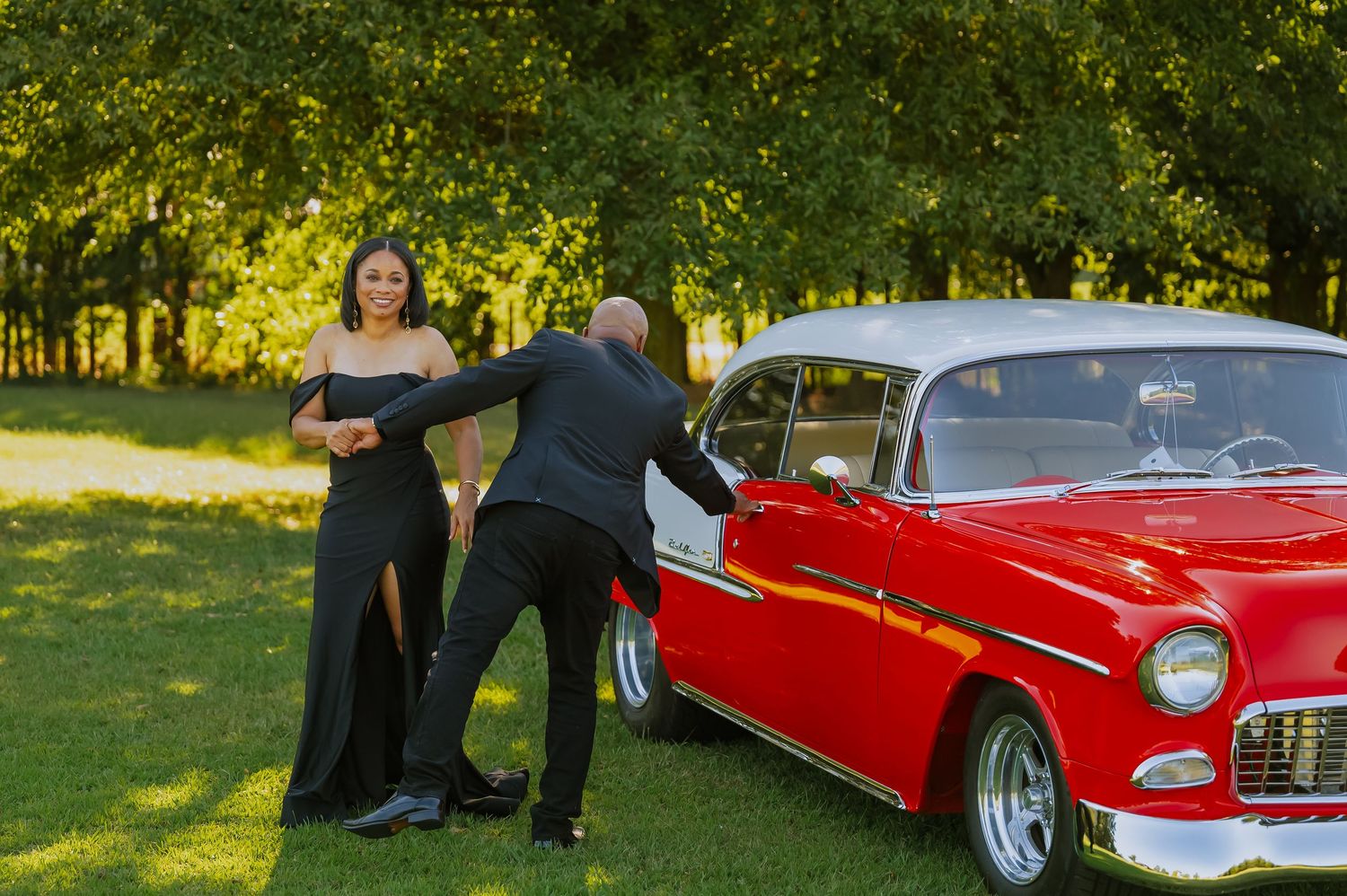 Vintage red Chevrolet car displayed on green lawn during outdoor photoshoot.