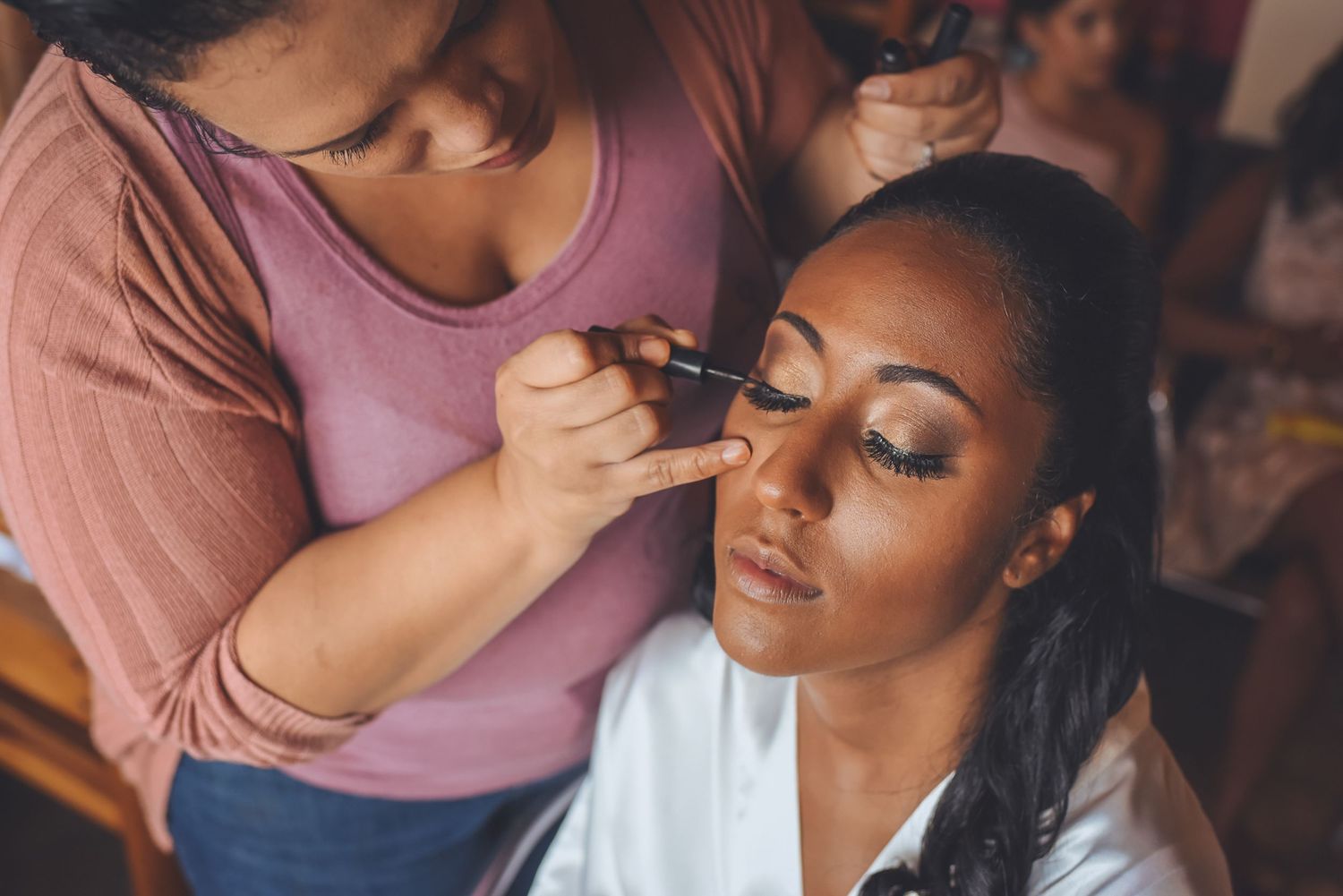 Makeup artist applies cosmetics during wedding preparation.