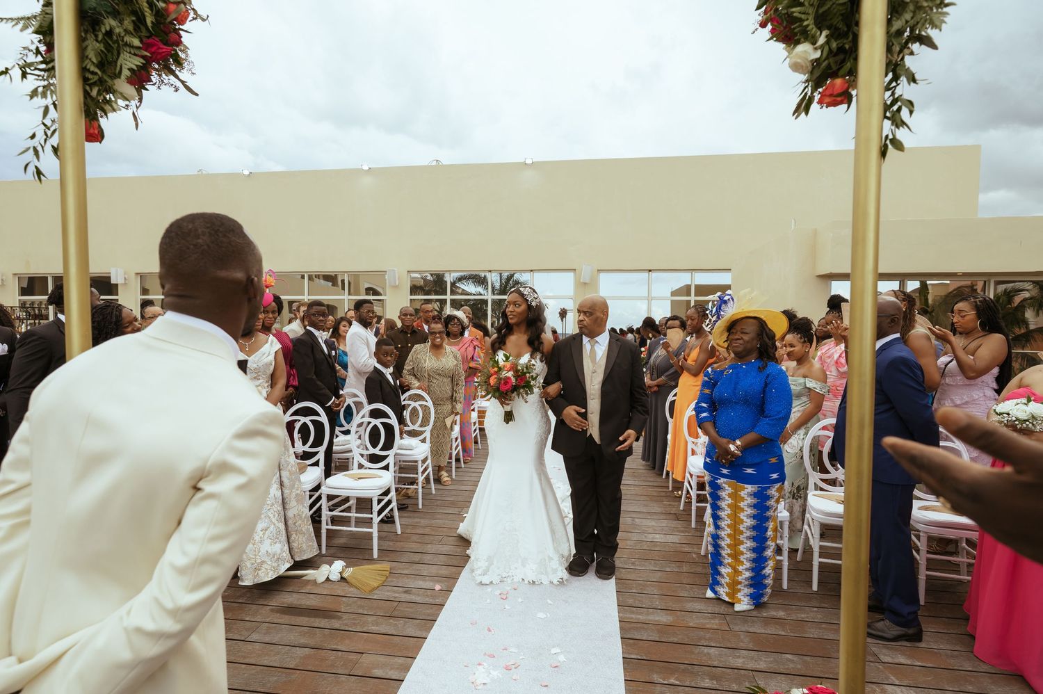Wide shot of wedding ceremony setup with white chairs and floral decorations on outdoor deck.