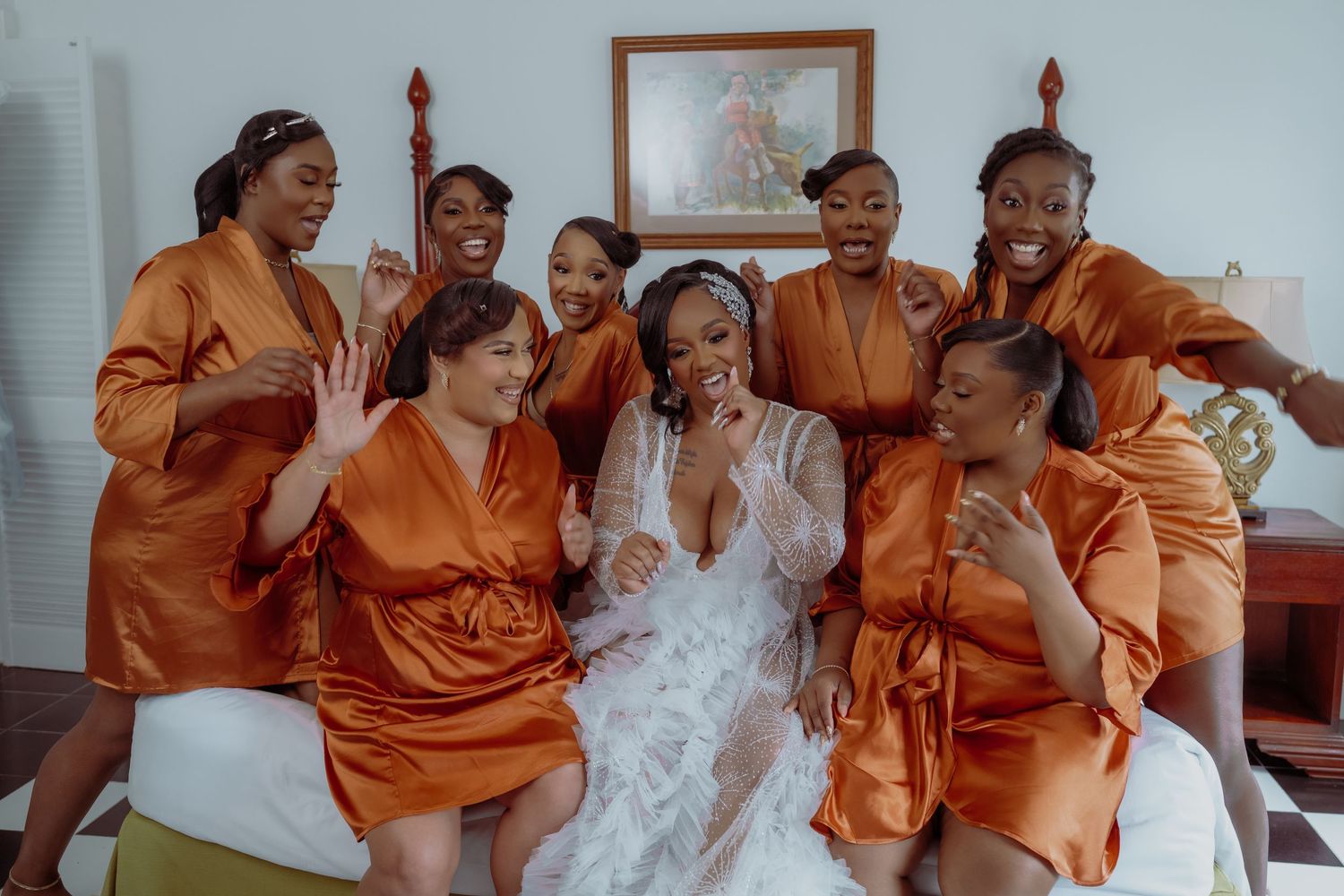 Wedding party wearing vibrant orange attire seated together during celebration. Luxury wedding photography at Half Moon Montego Bay