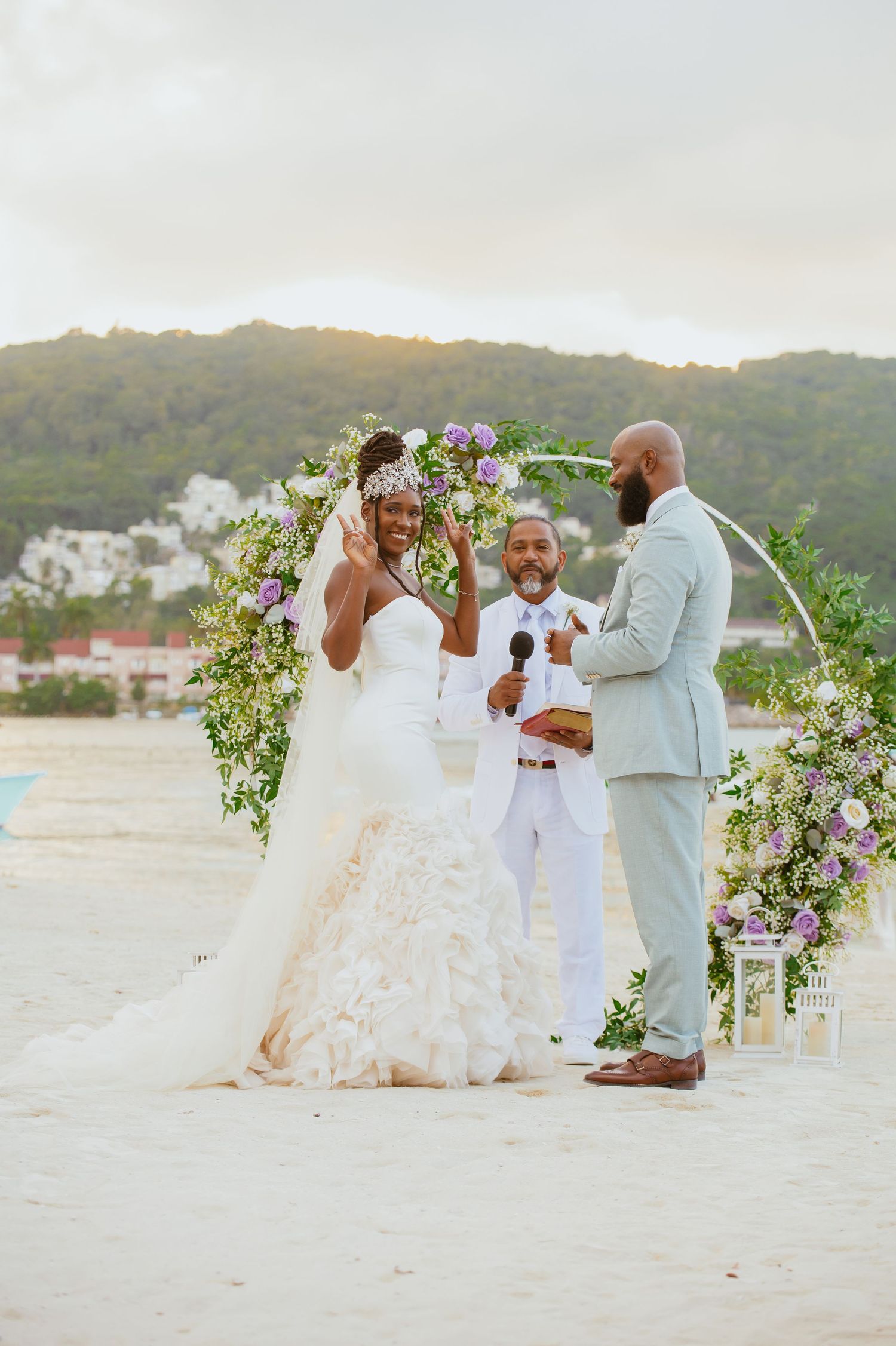 Wedding couple sharing an intimate moment under a floral arch on a beach at sunset.