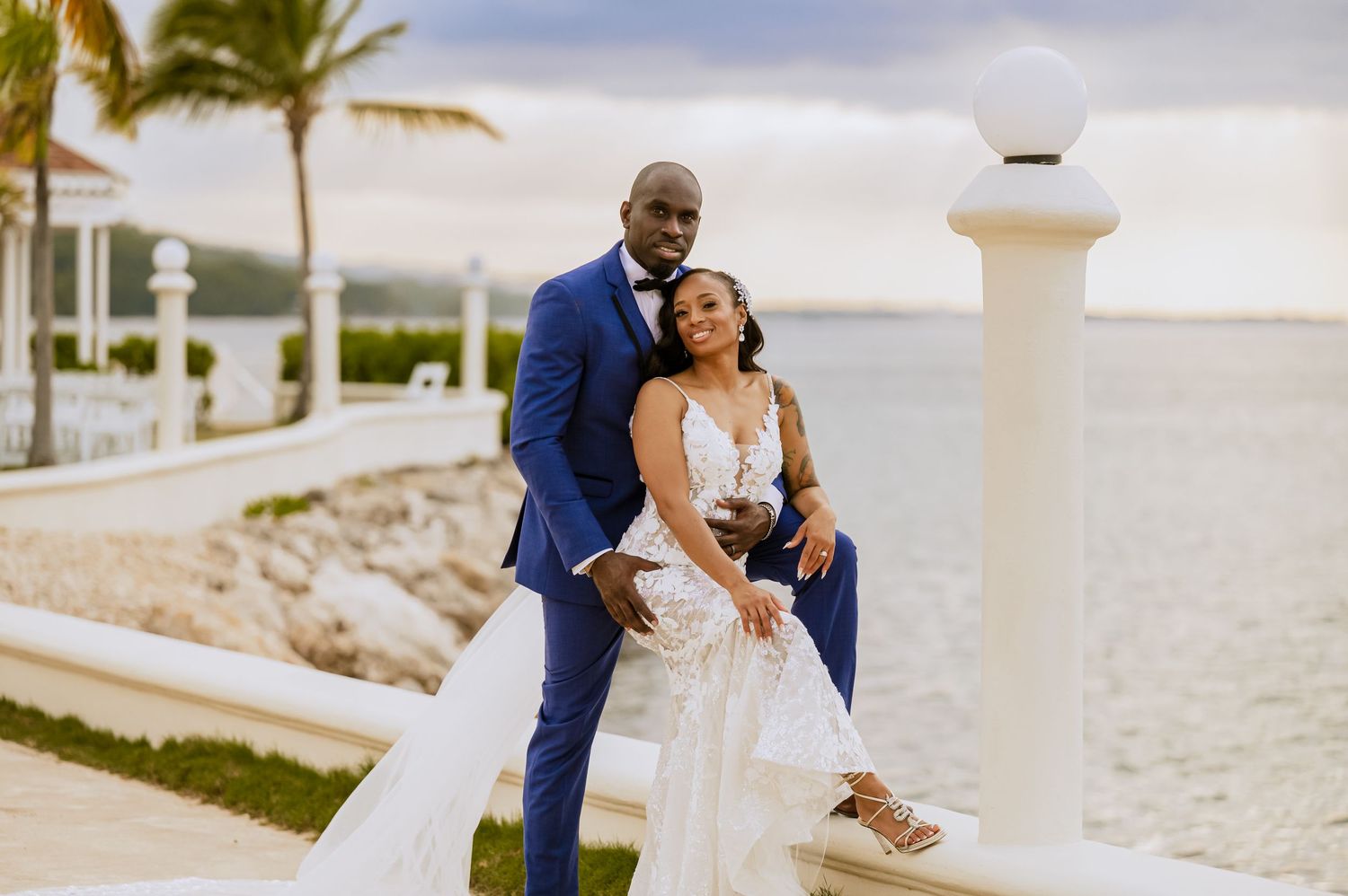 Wedding couple shares tender moments along a coastal walkway with scenic ocean views.