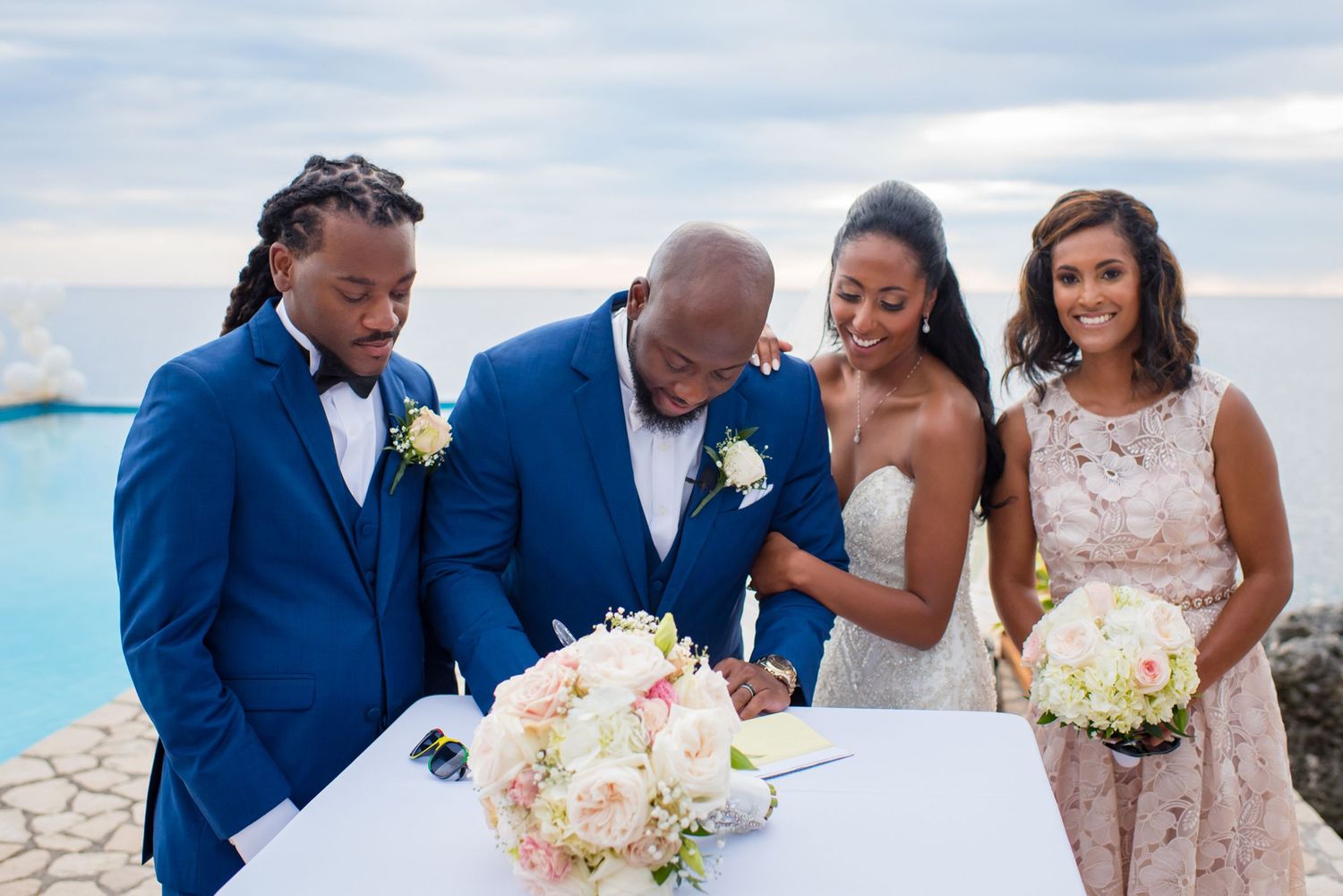 Wedding party gathered on tropical beach for outdoor ceremony photos.