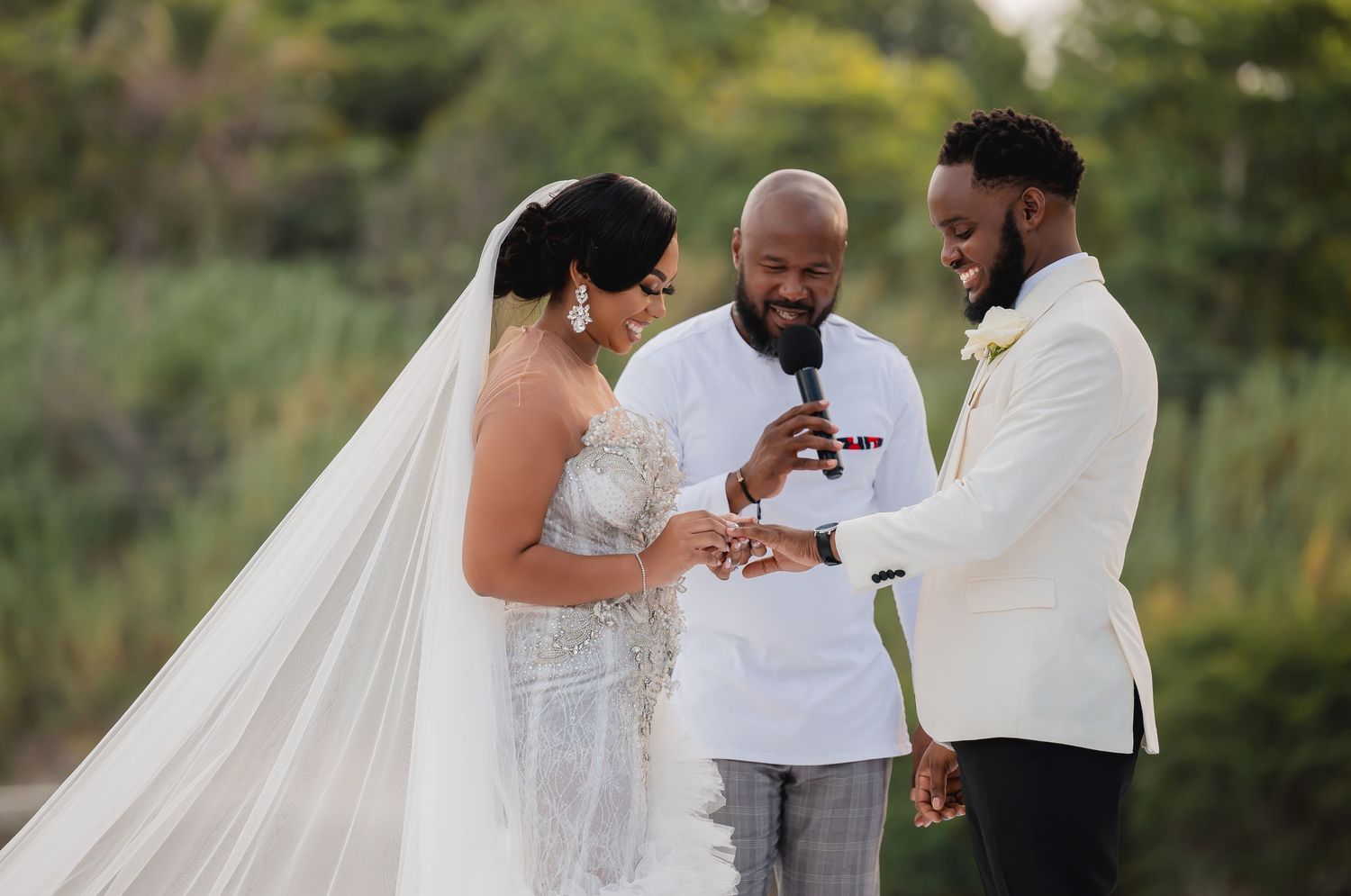 A beautiful outdoor wedding ceremony with the couple and officiant sharing a joyful moment during the vows.