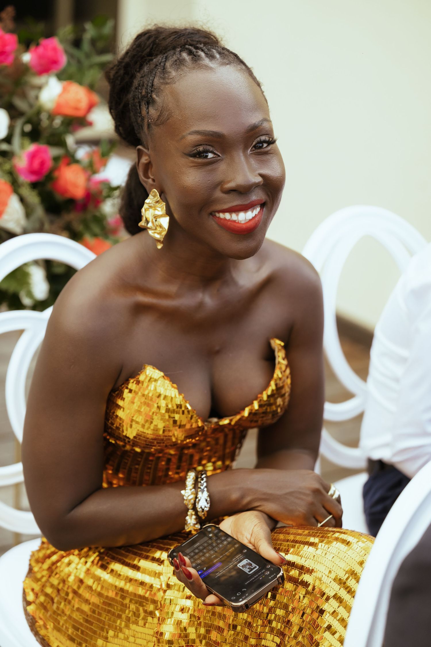 Wedding guest in stunning gold sequined dress smiles while seated at reception.
