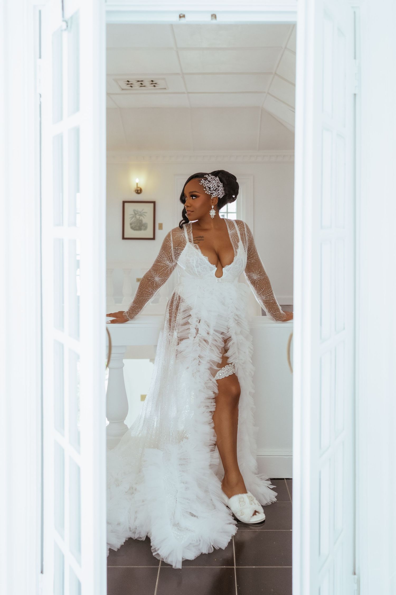 Elegant white feathered wedding dress displayed in a bright interior room with classic moldings.