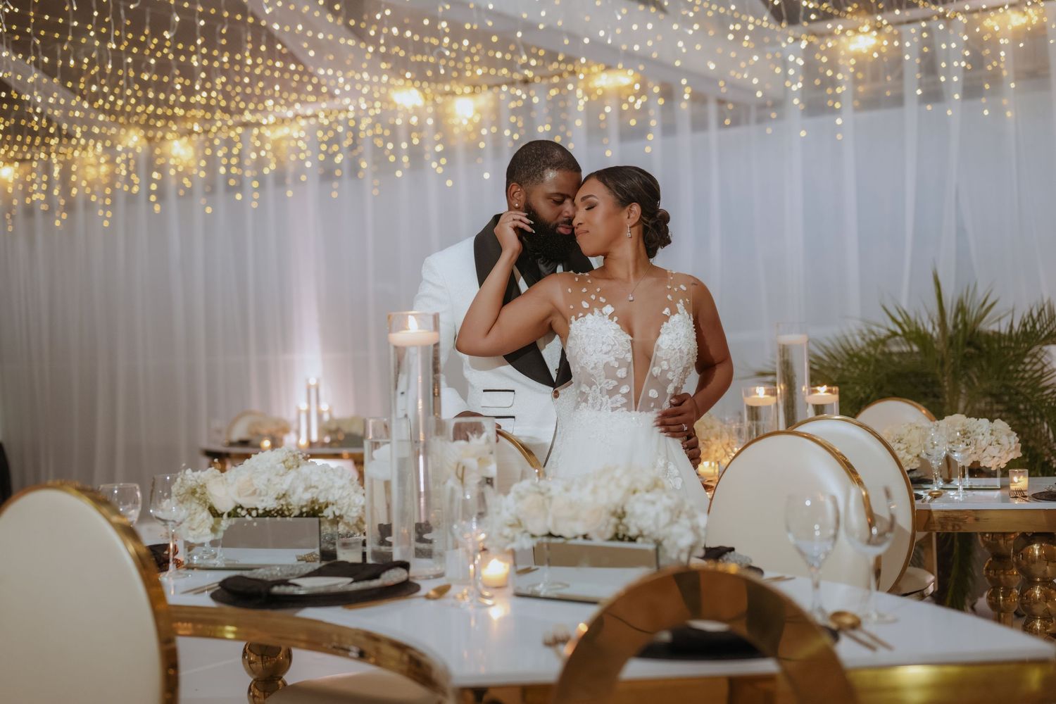 Wedding reception venue decorated with romantic string lights and white table settings.