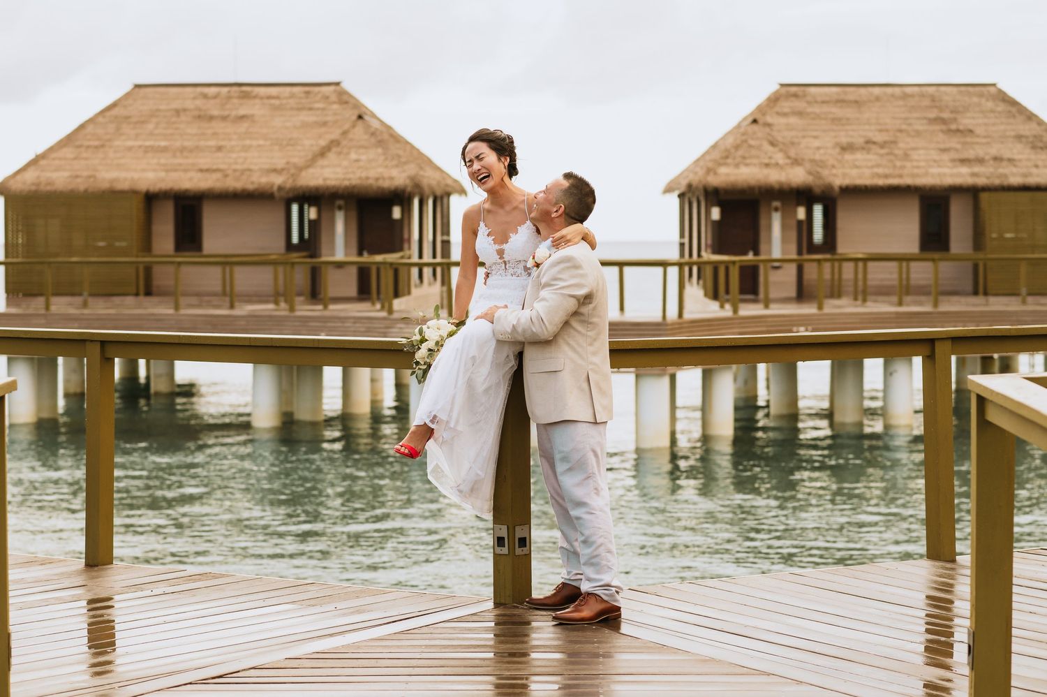 Wedding couple sharing intimate moments on overwater bungalow deck.