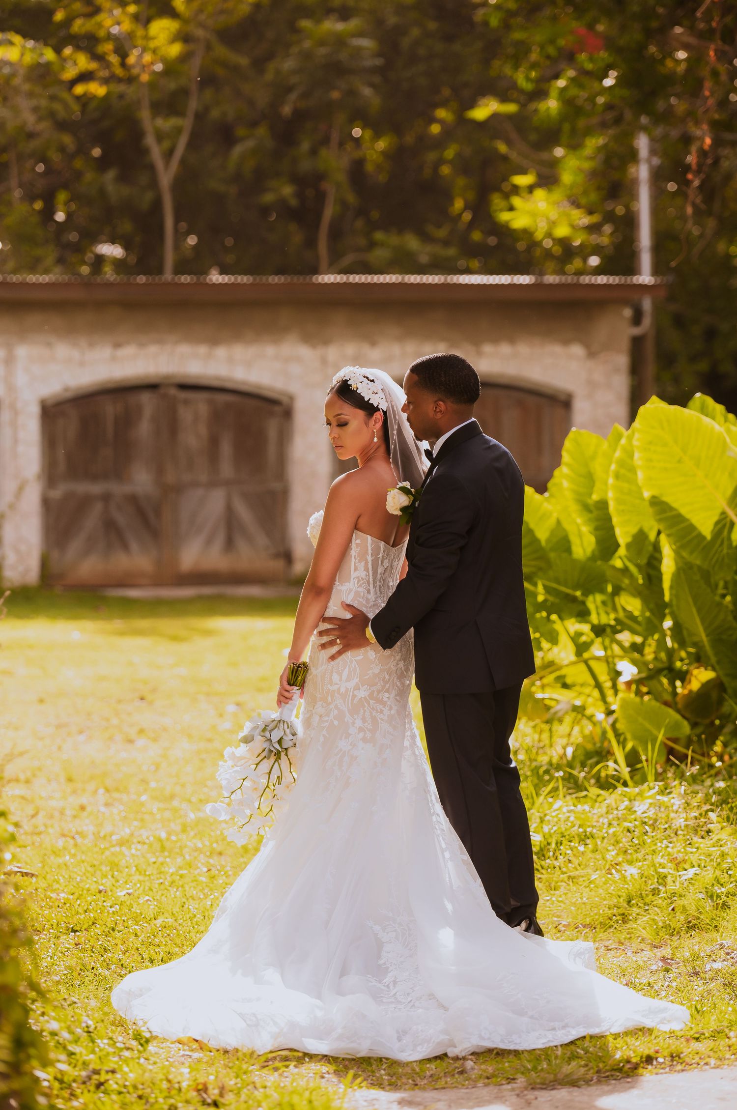 Sunlit wedding portraits in a garden with golden light filtering through the trees.