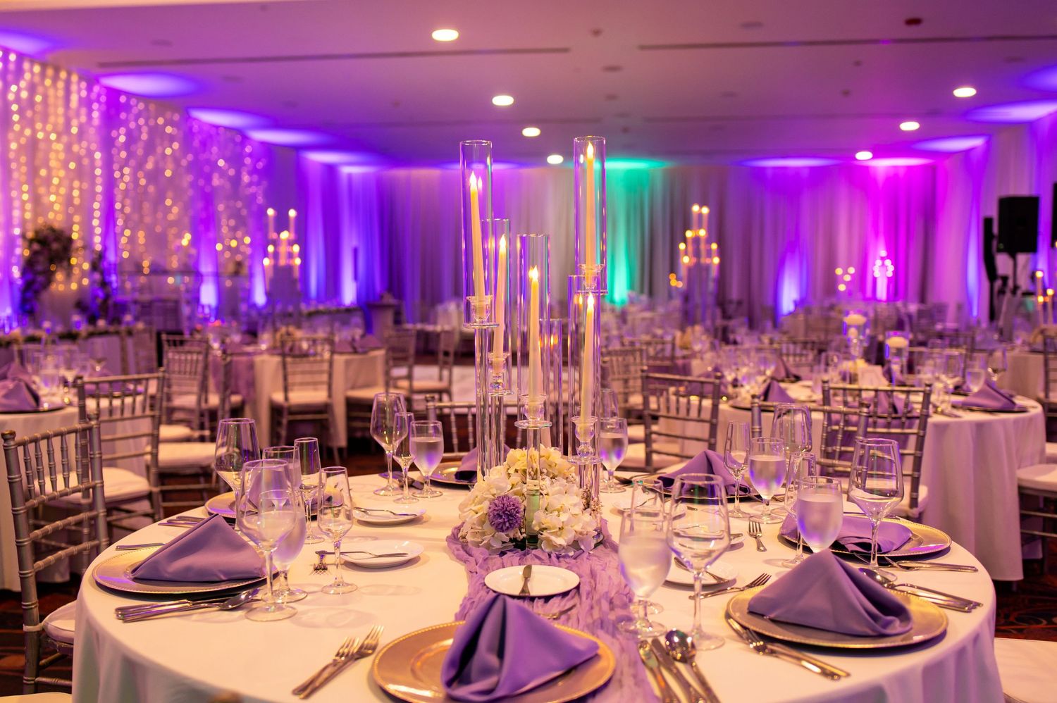 Luxurious wedding reception tables set with purple accents and dramatic mood lighting.
