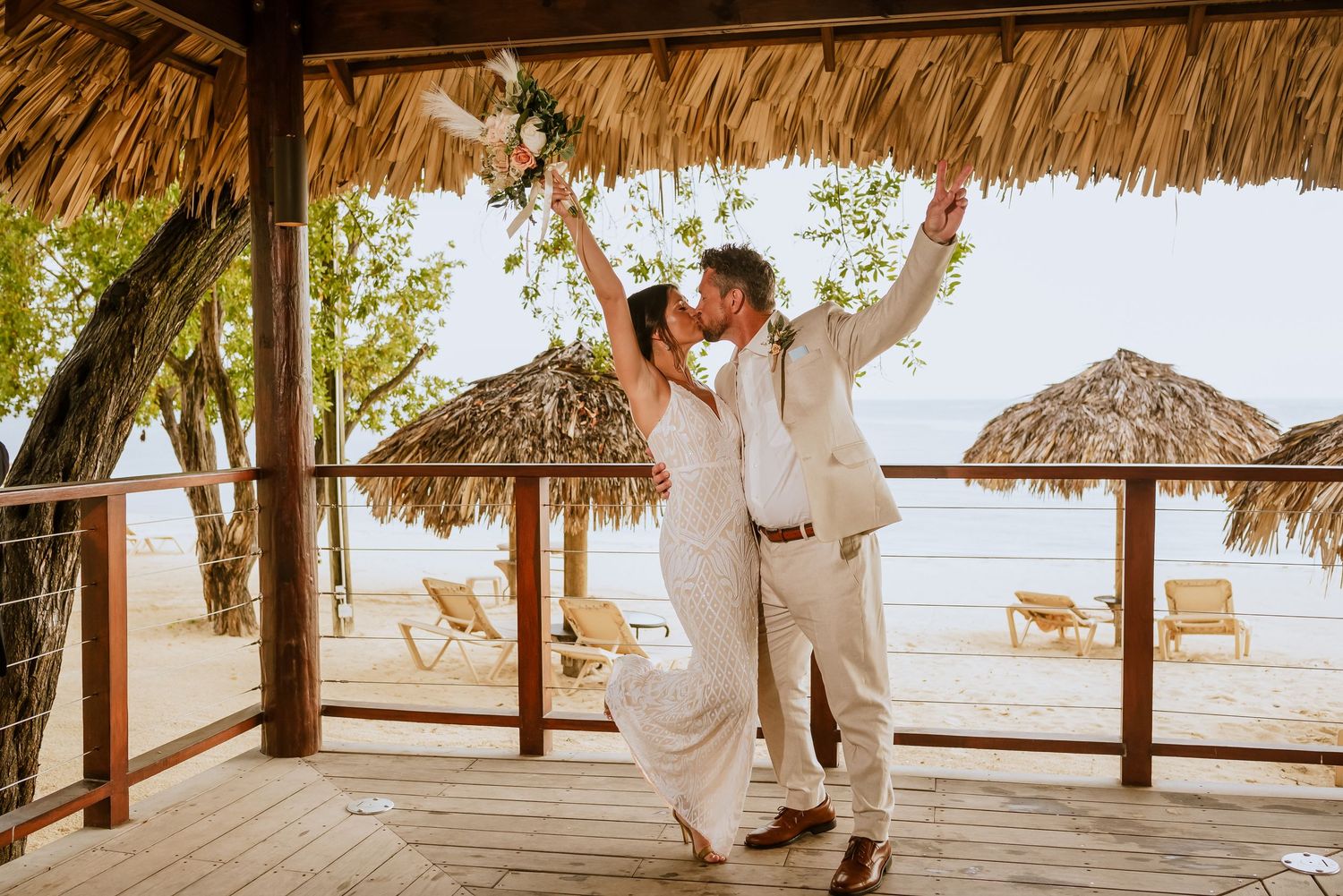 Wedding celebration moments captured under a thatched palapa with beach views.