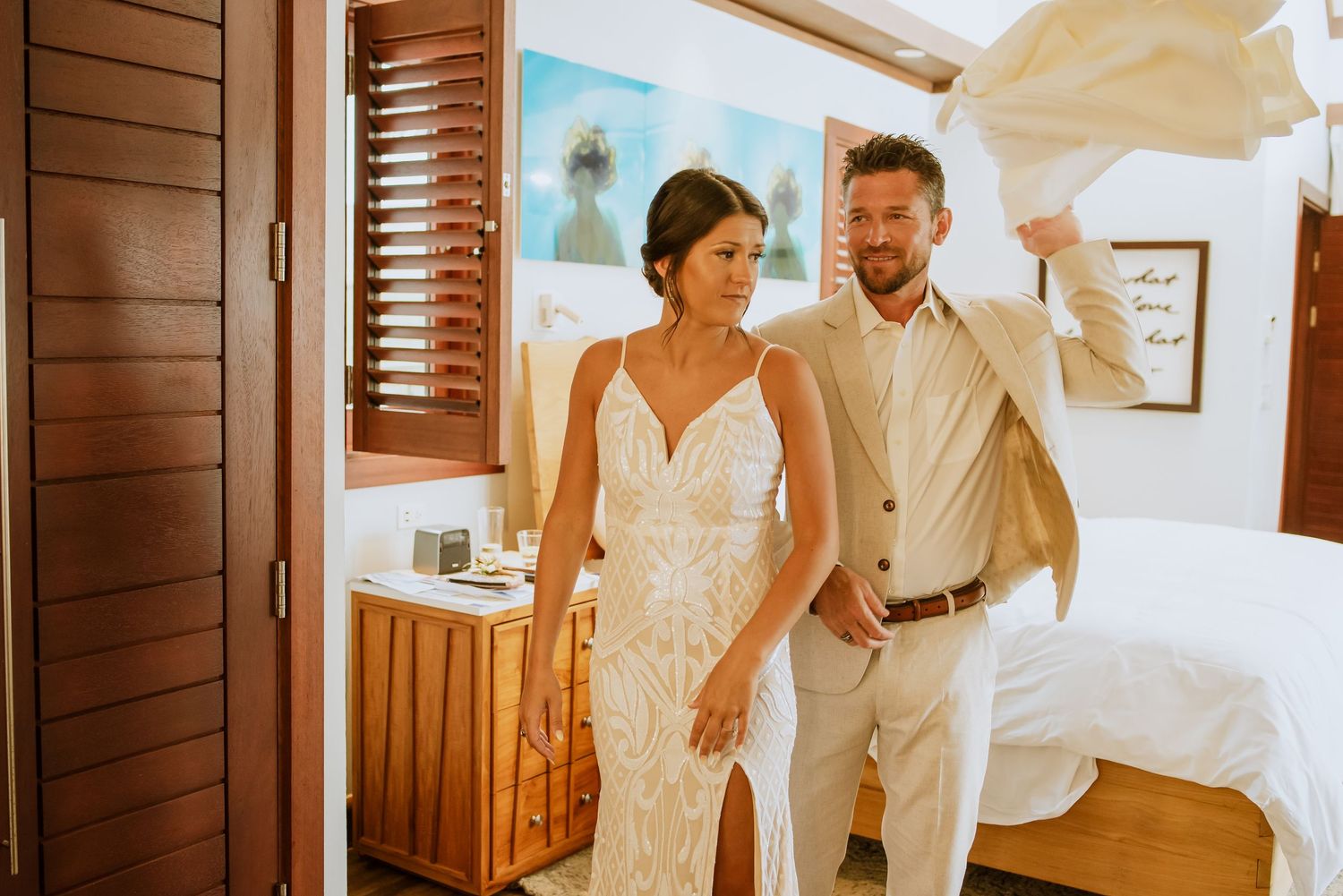 Wedding preparation scene with white dress and natural light streaming through windows.