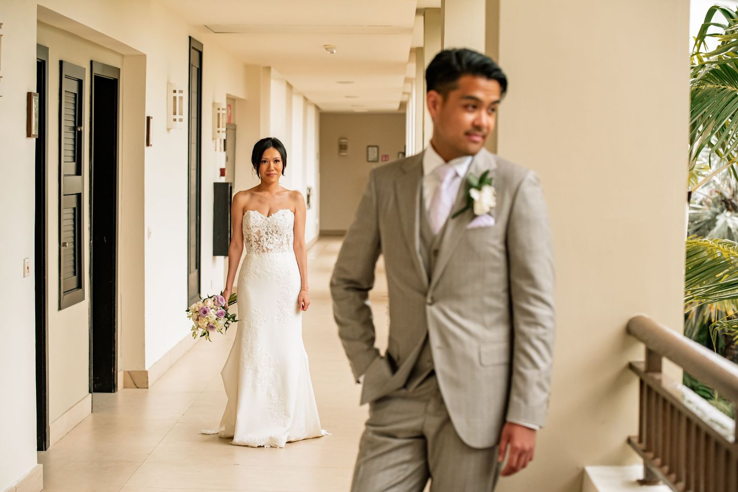 Romantic first look sequence between bride and groom in a light-filled corridor.